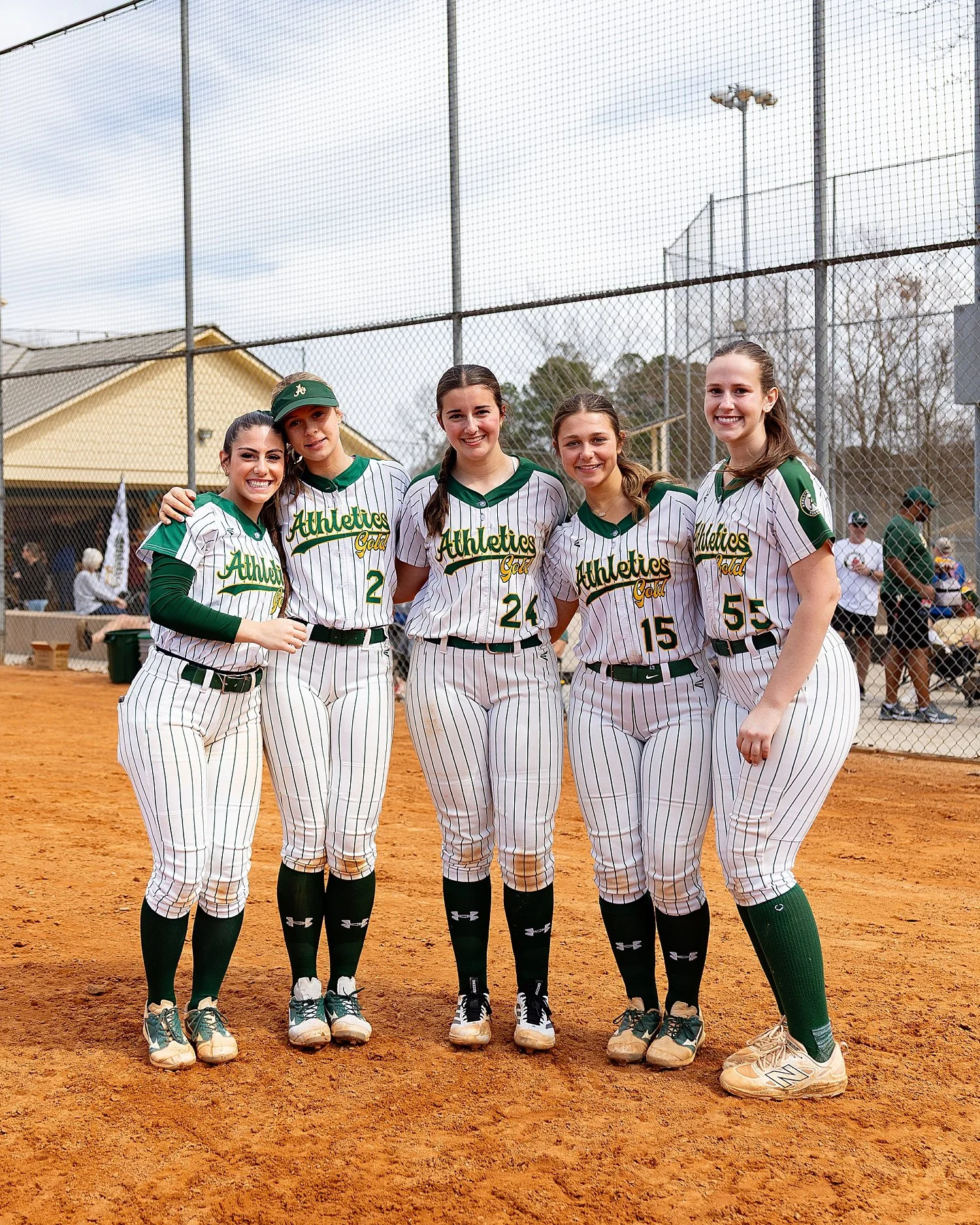  five girls stand near dugout on field on travel softball teams 