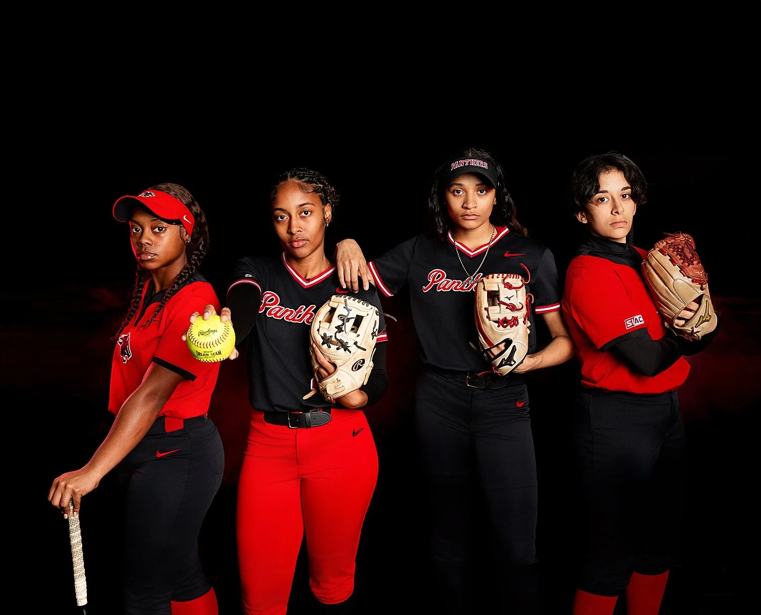  group of four softball players stand together in uniform for a media day 