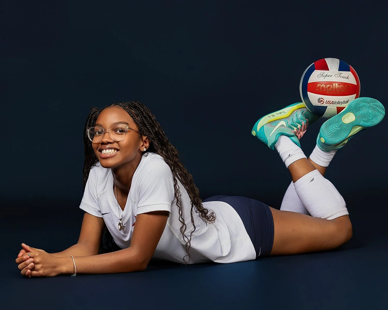  athlete lies on the ground with the volleyball propped on her feet by Atlanta sports photographer 