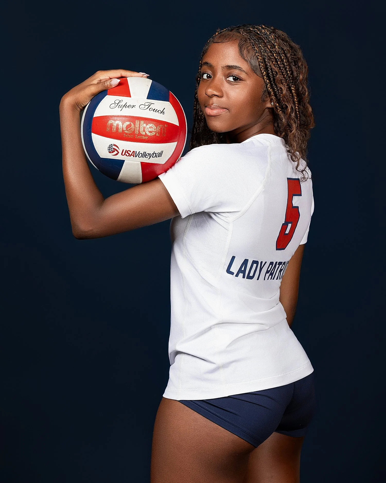  athlete holds volleyball in hand looking over her shoulder by Tiaras Monet Photography 
