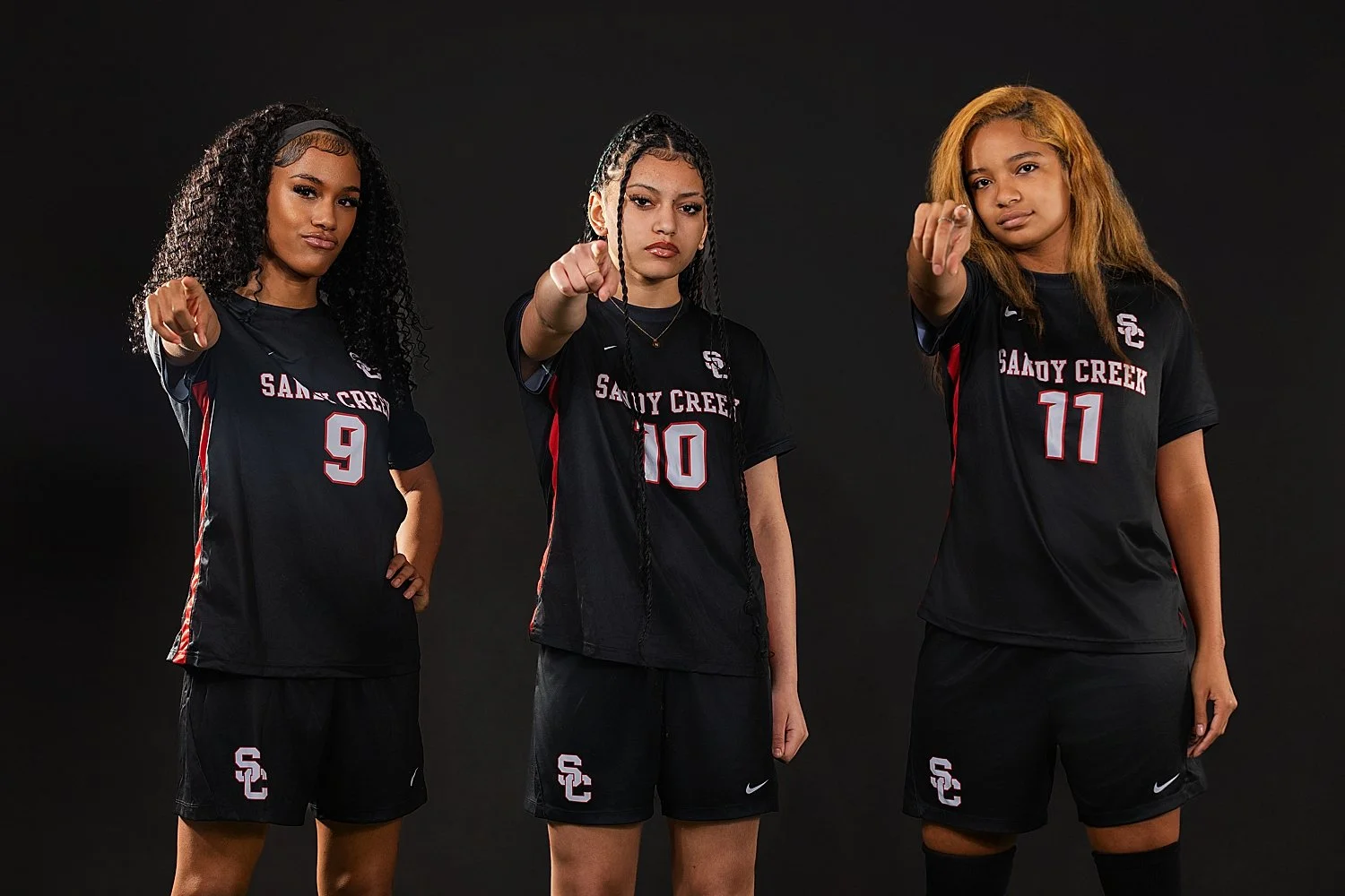 three women stand in sports uniform and point by Tiaras Monet Photography