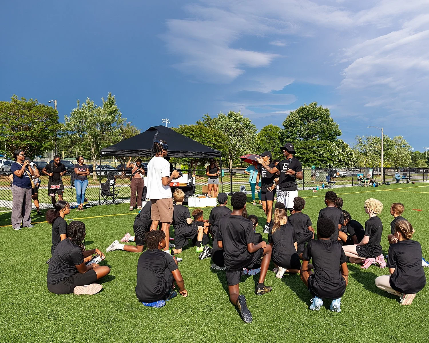 flag football team sitting on turf listening to coach by Atlanta photographer