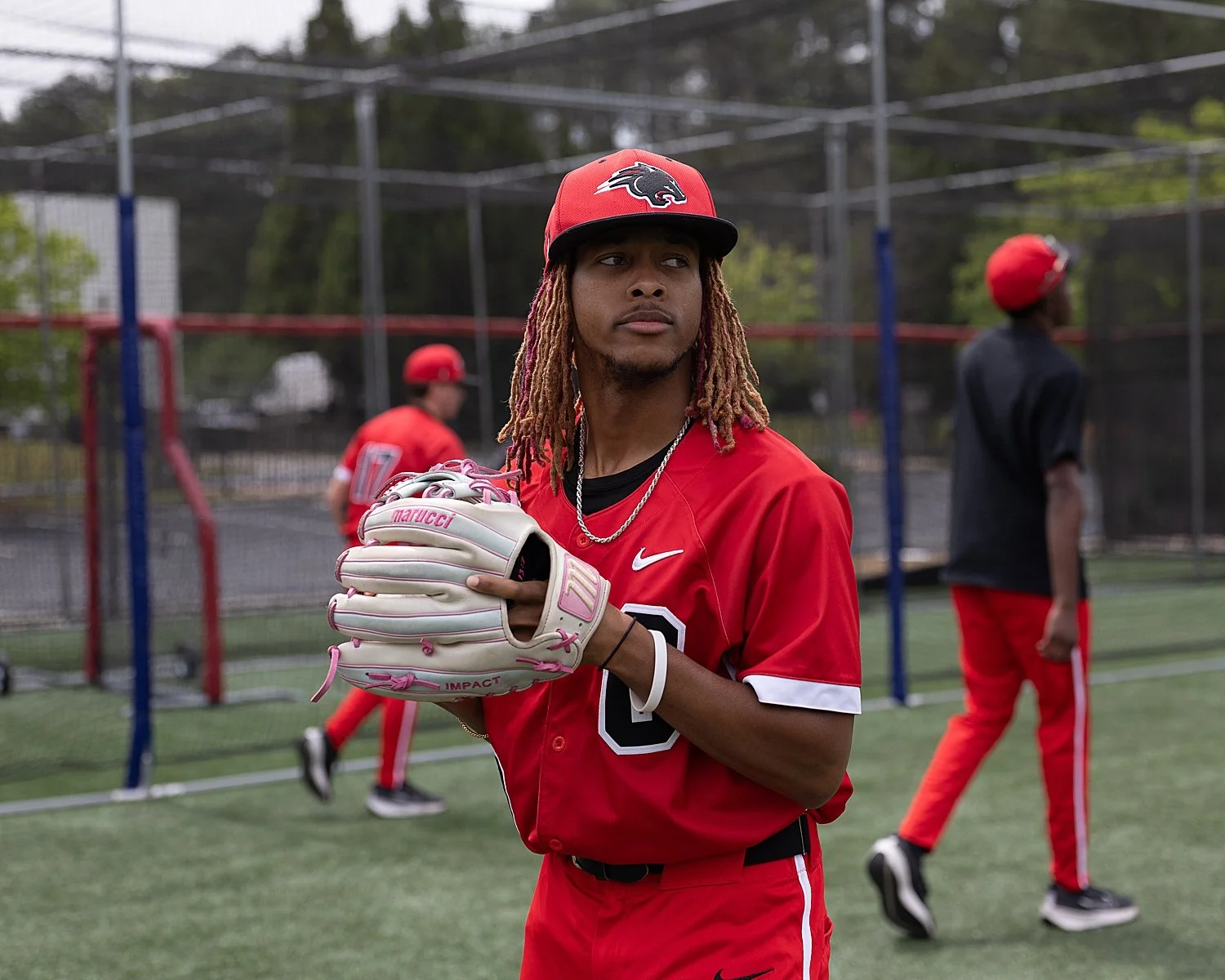 man in red hat with glove stands on baseball field by Atlanta Sports Photography
