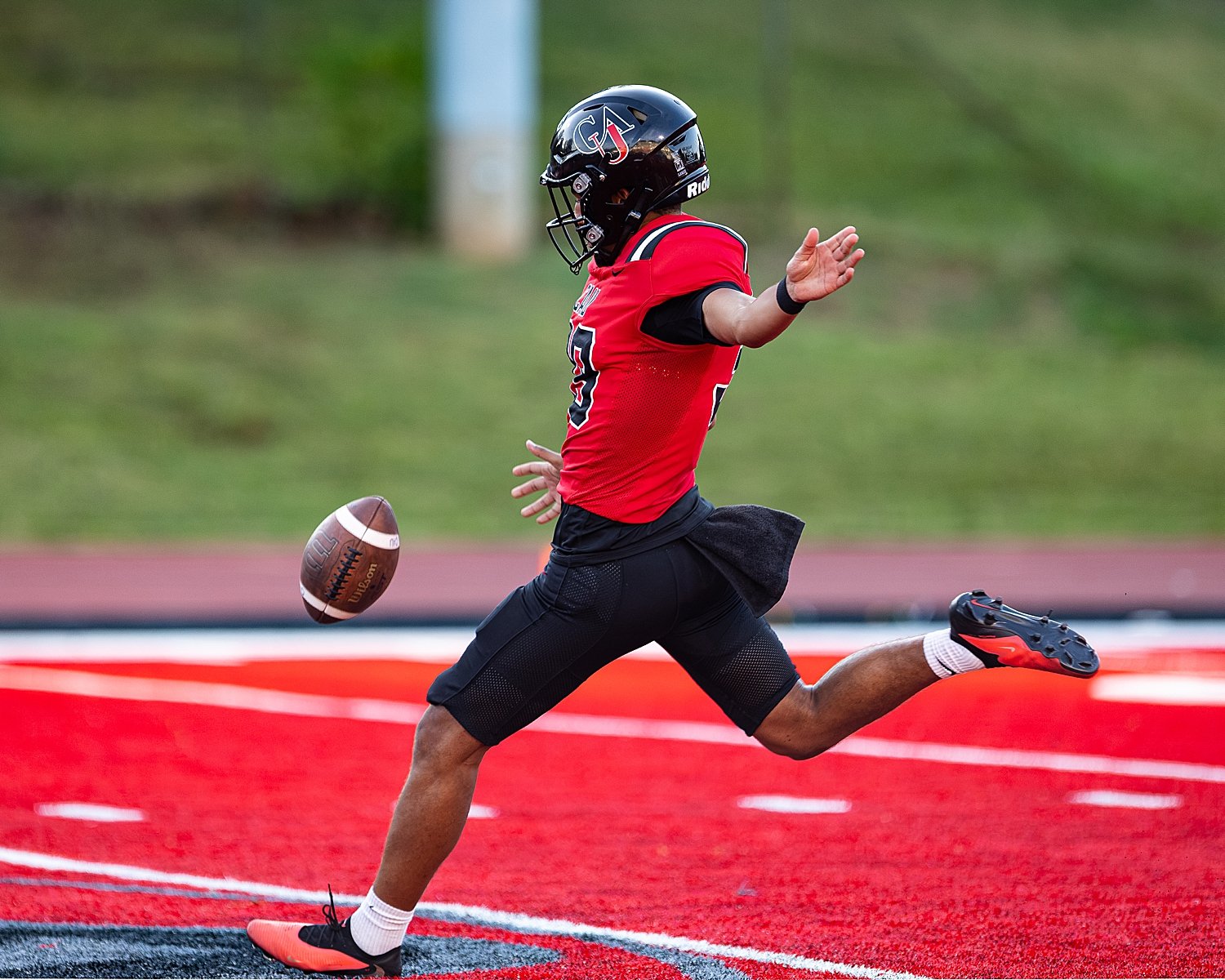 athlete kicks ball on field in red uniform by Tiaras Monet Photography