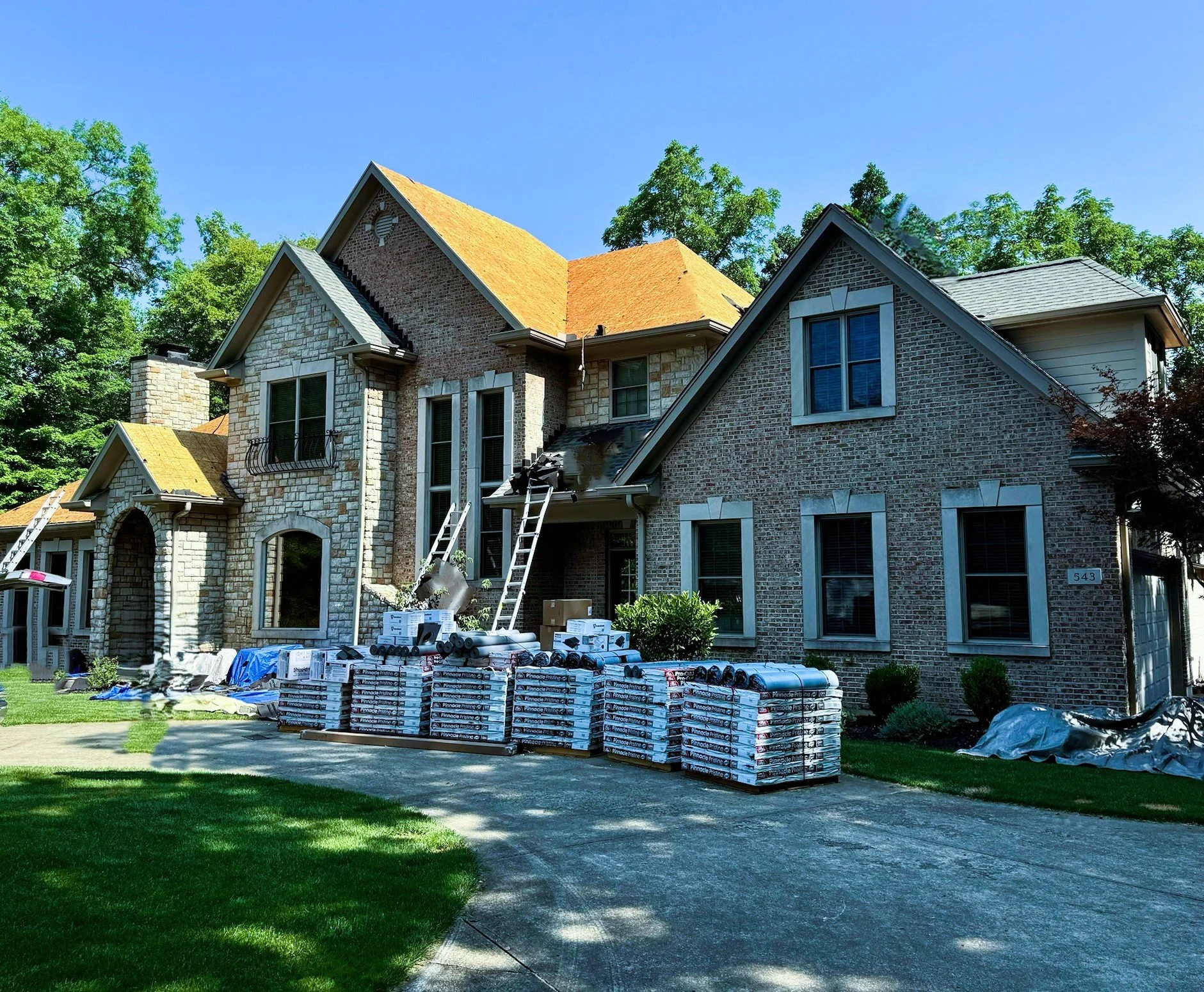 House under construction with roofing materials and supplies in the front yard.