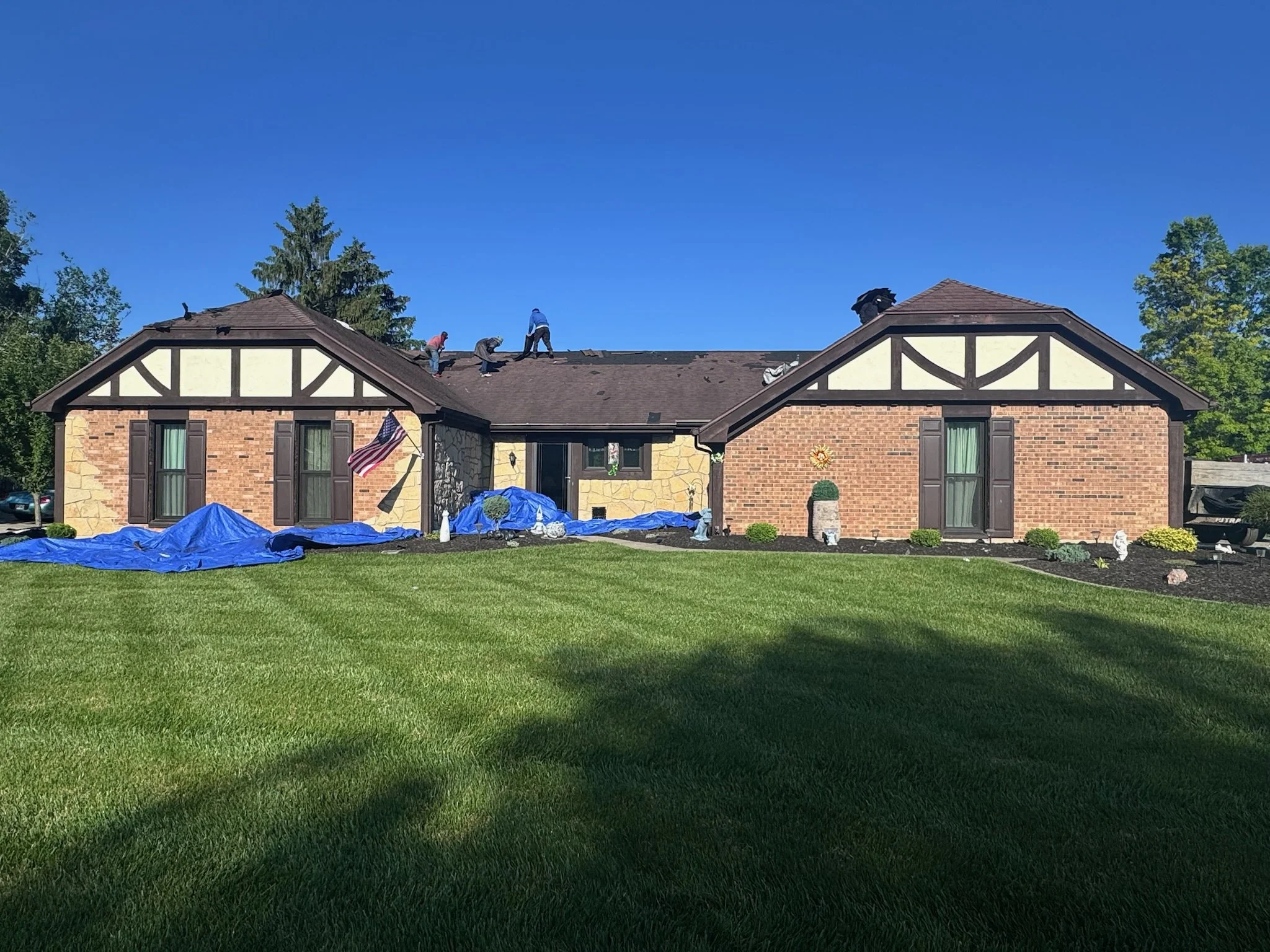 House under construction with roofing materials and supplies in the front yard.