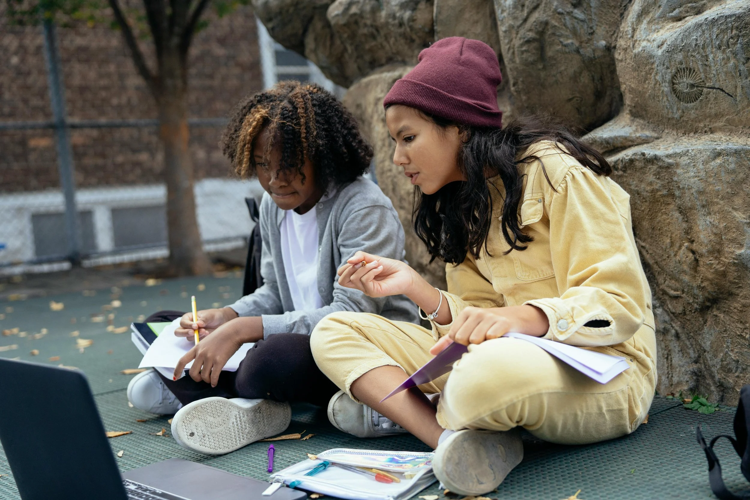 Two teenage girls sitting outside doing art together
