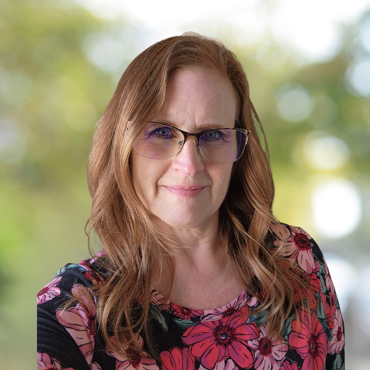 Portrait of Robyn Lloyd, licensed professional counselor at Sanity Center, smiling outdoors with greenery in the background.