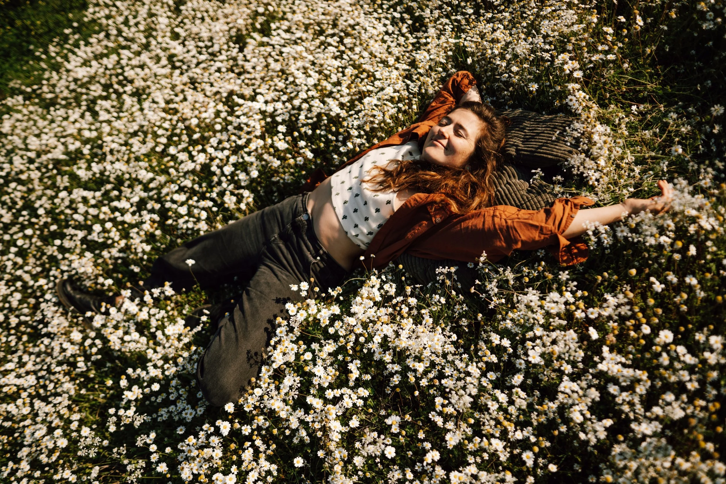 woman lying in a field of flowers having just done a TRE session