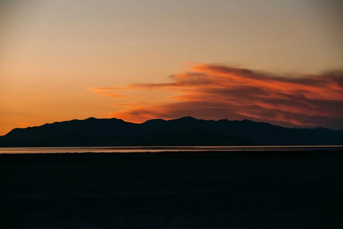 Silhouette of mountains at sunset with colorful sky and clouds.