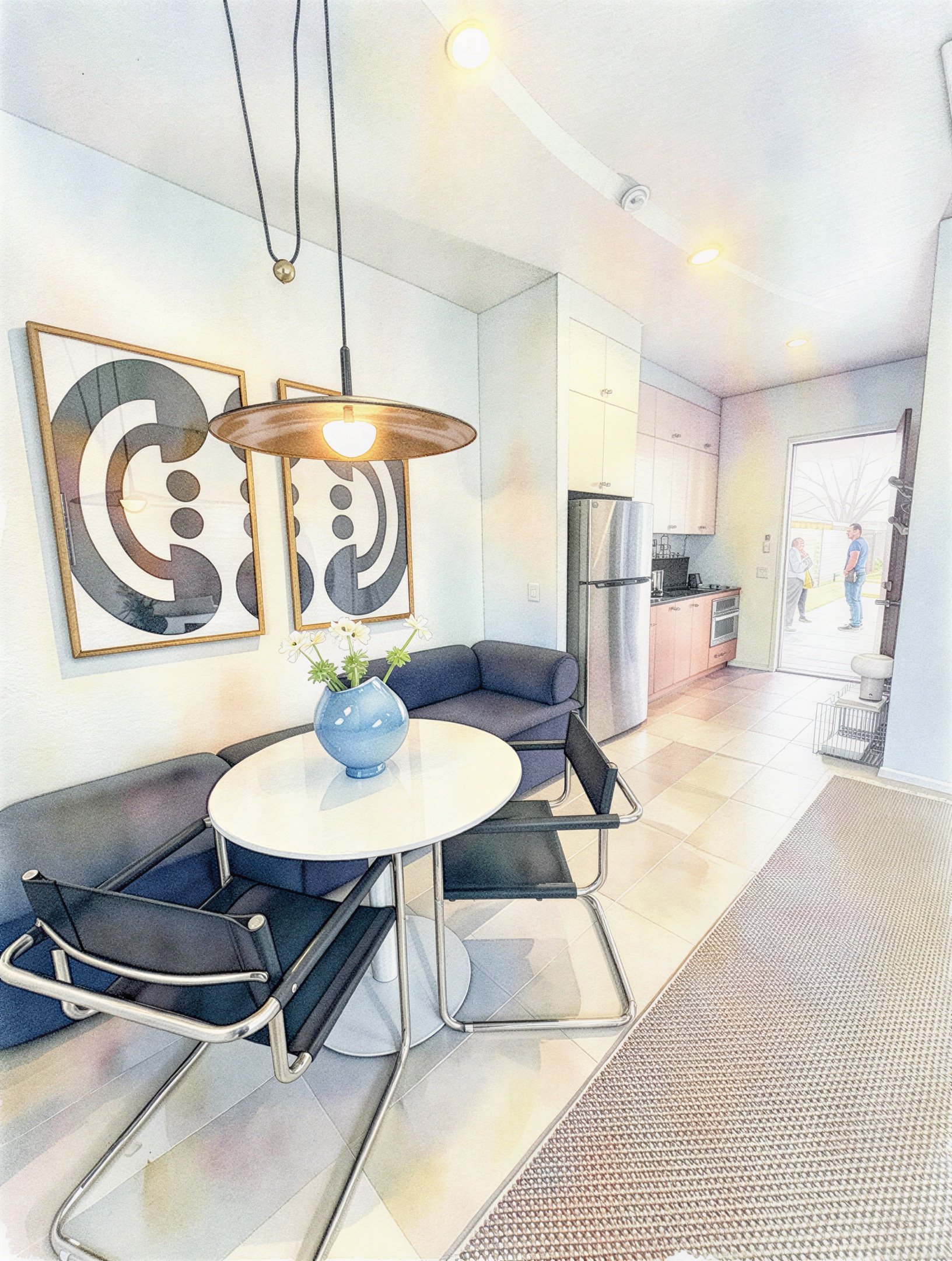 Dining area with a round white table, black chairs, a blue vase with flowers, and wall art behind the sofa with people visible outside.