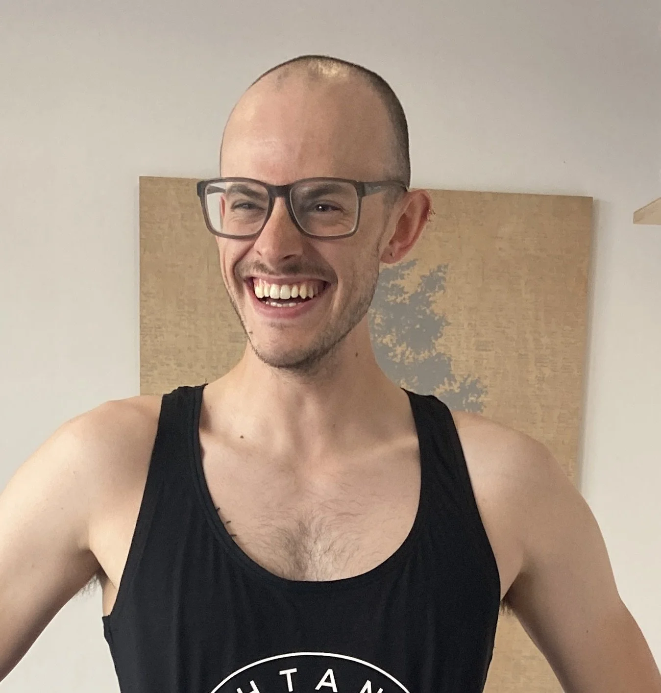 Two people sitting indoors, smiling and holding cups, enjoying a casual moment together.