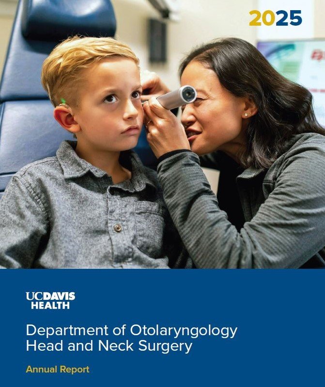 A woman examines a young boy's ear with an otoscope in a medical setting. The boy looks to the side, while the woman is looking through the otoscope at his ear.