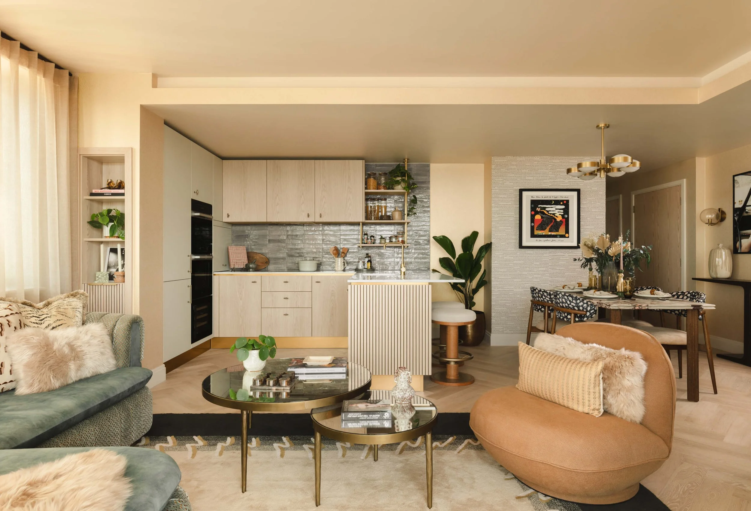 Open-concept living room and kitchen with modern decor, plush furniture, and a dining table with floral arrangements.