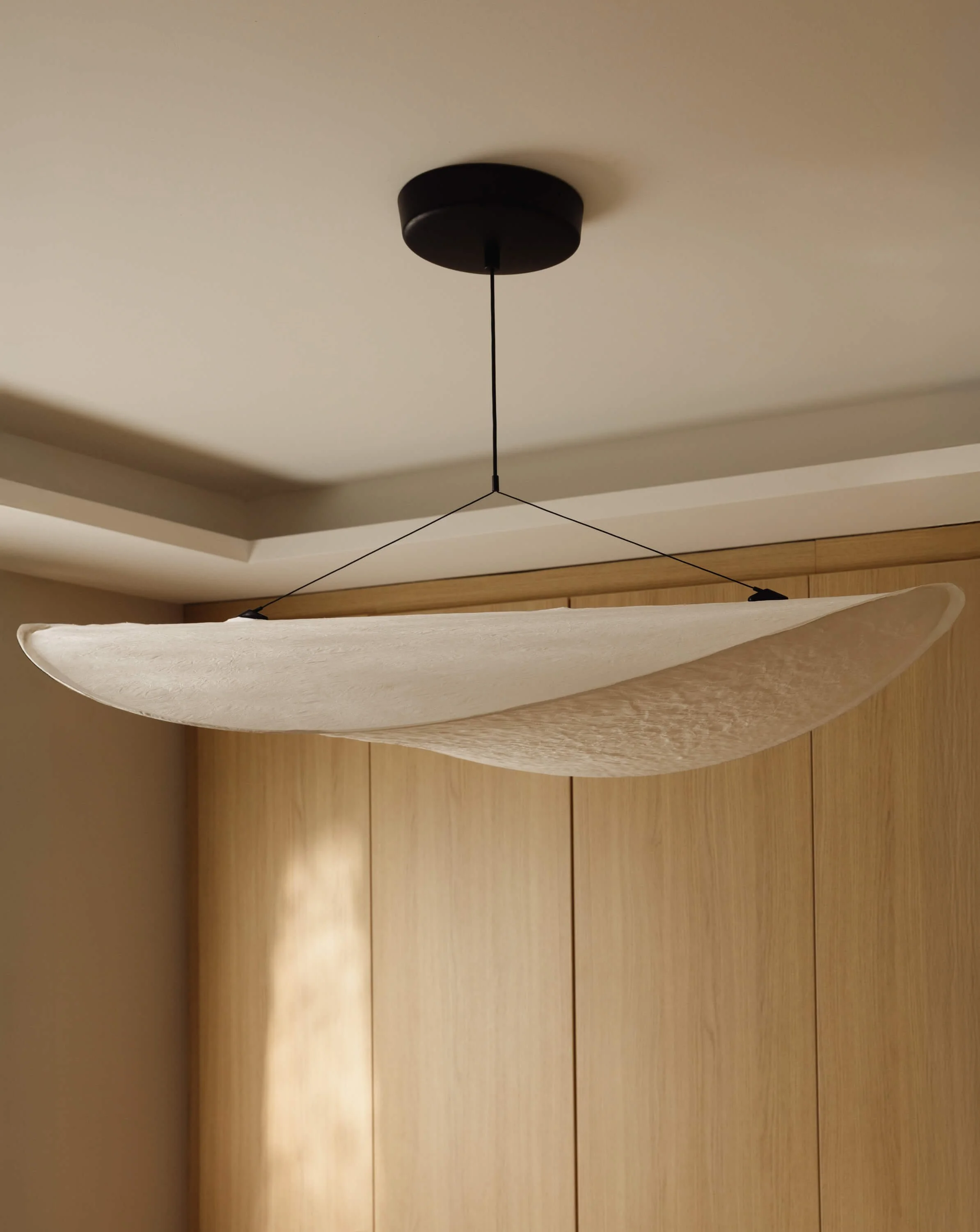 Ceiling light fixture with a white, curved fabric shade