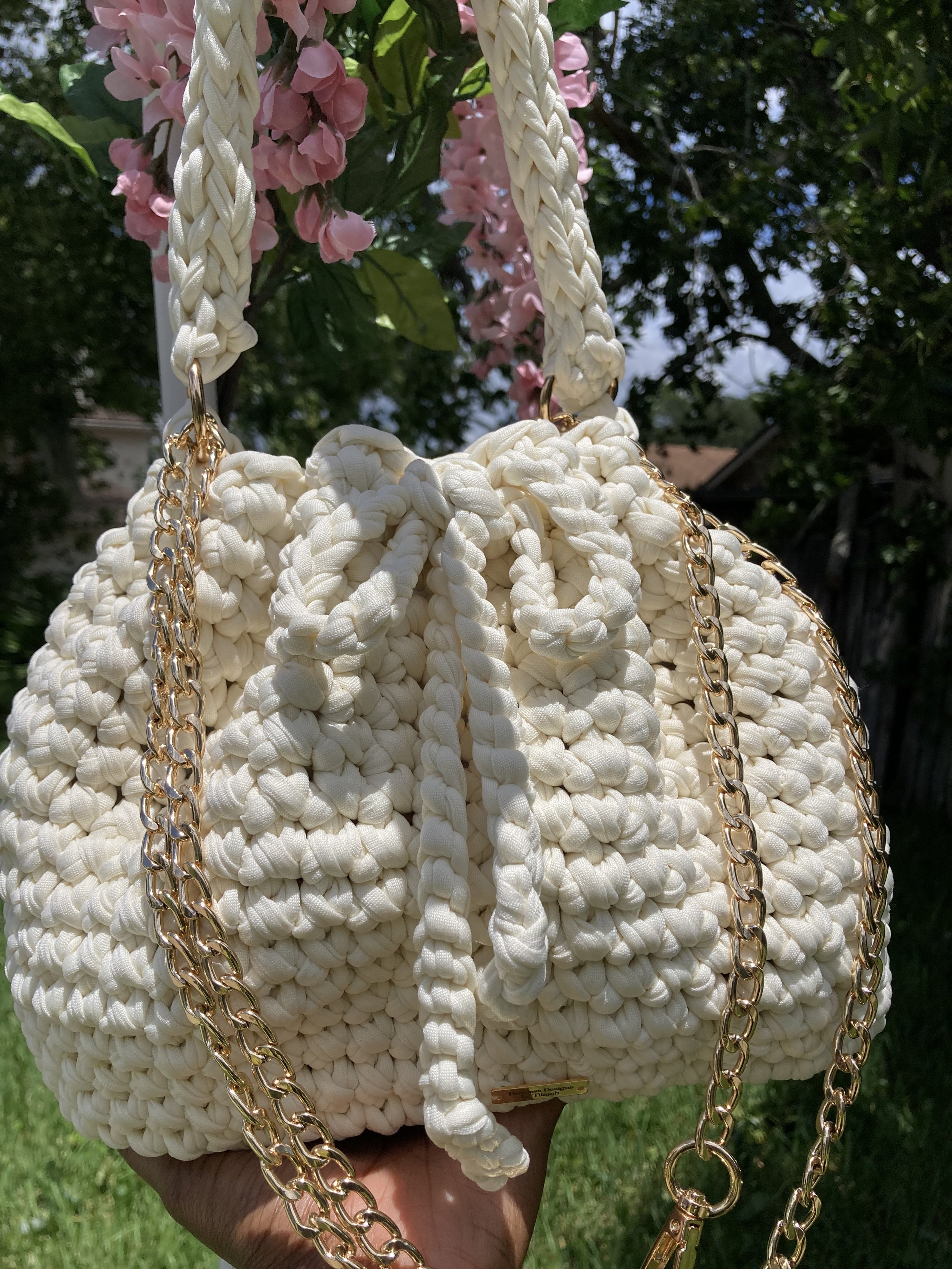 cream crochet bucket handbag with a crochet purse strap and a drawstring bow