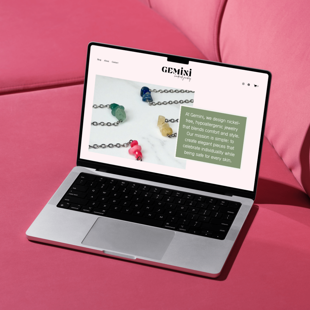 A laptop displaying the homepage of Gemini Jewelry, showcasing colorful gemstone jewelry on a marble background. The website's text highlights the brand's focus on hypoallergenic, nickel-free jewelry designed for individuality and safety.