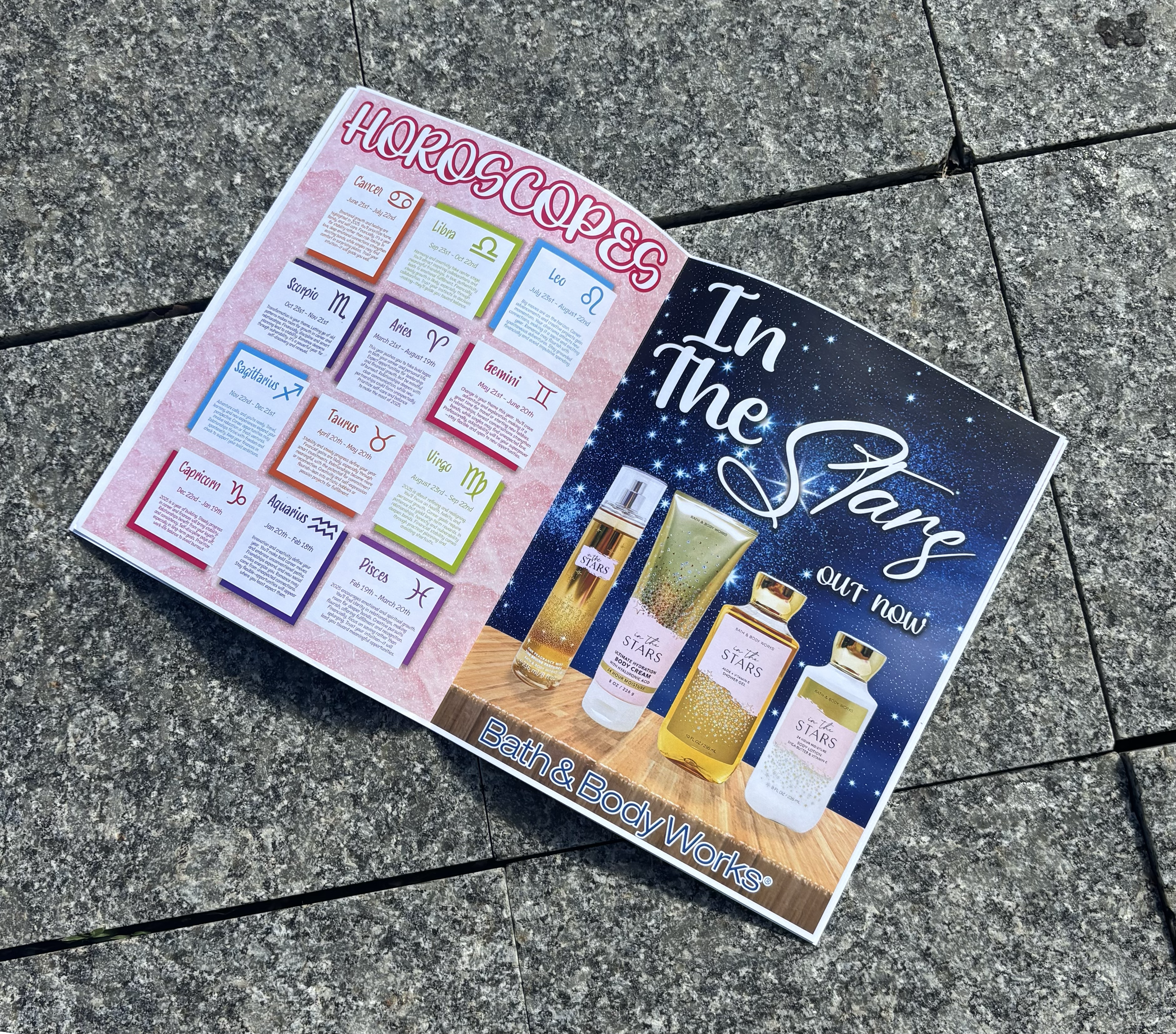 Colorful advertisement for Bath & Body Works products featuring zodiac signs and their date ranges, with images of four star-themed bottles of body spray, lotion, and perfume on a wooden surface, titled "In The Stars Out Now."