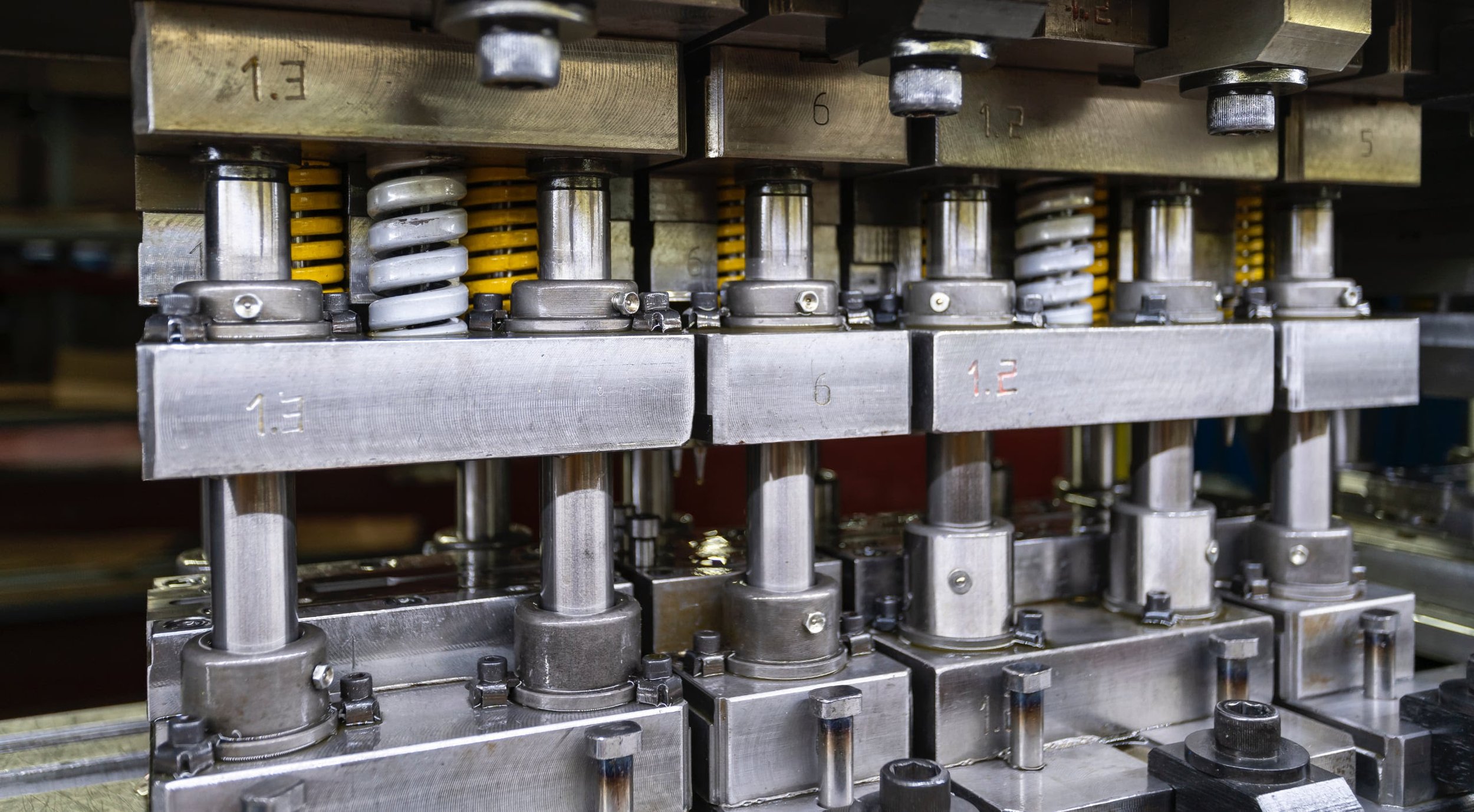 Close-up of a machine with metal components, springs, and bolts in an industrial setting.