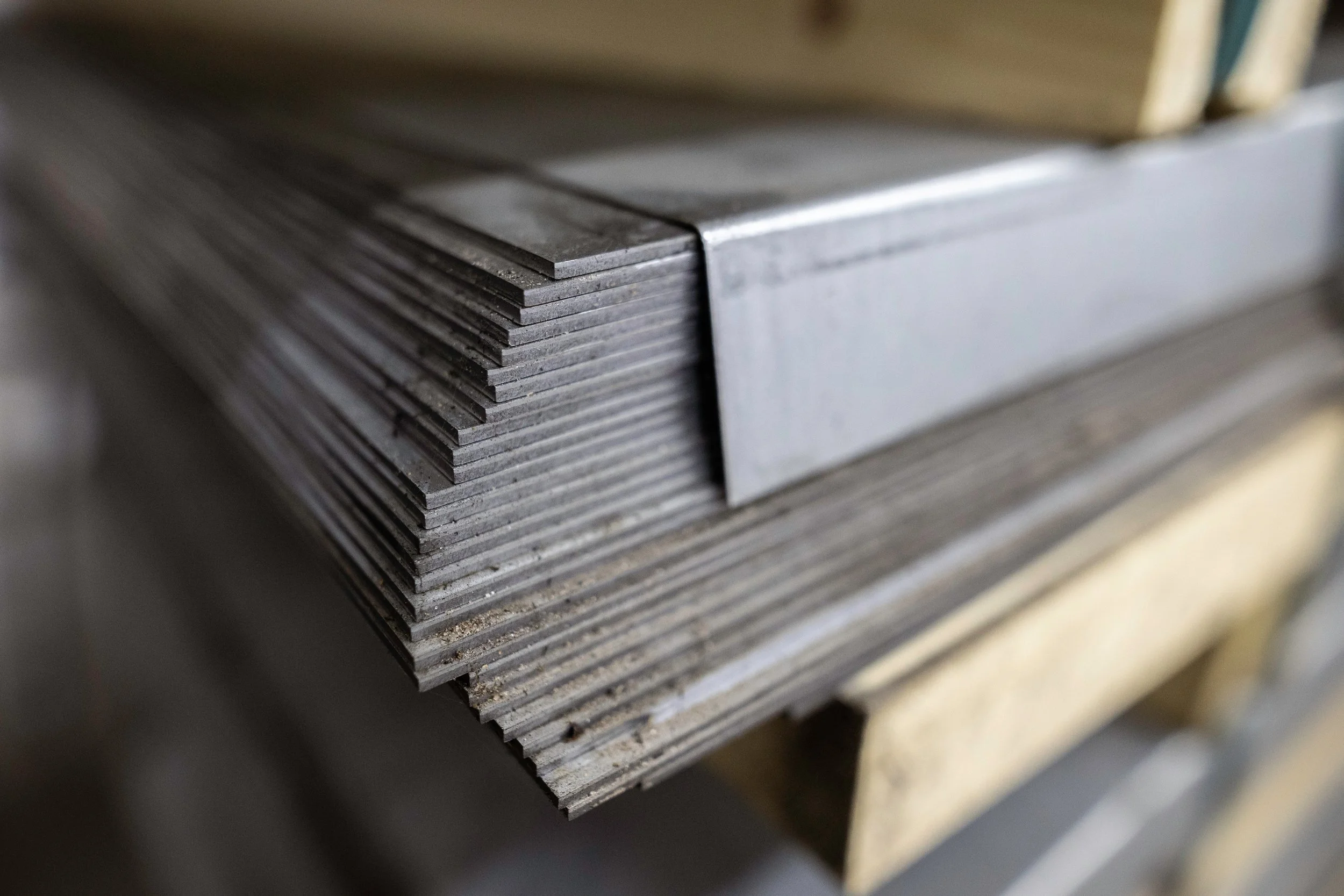 Stack of metal sheets resting on a wooden surface.