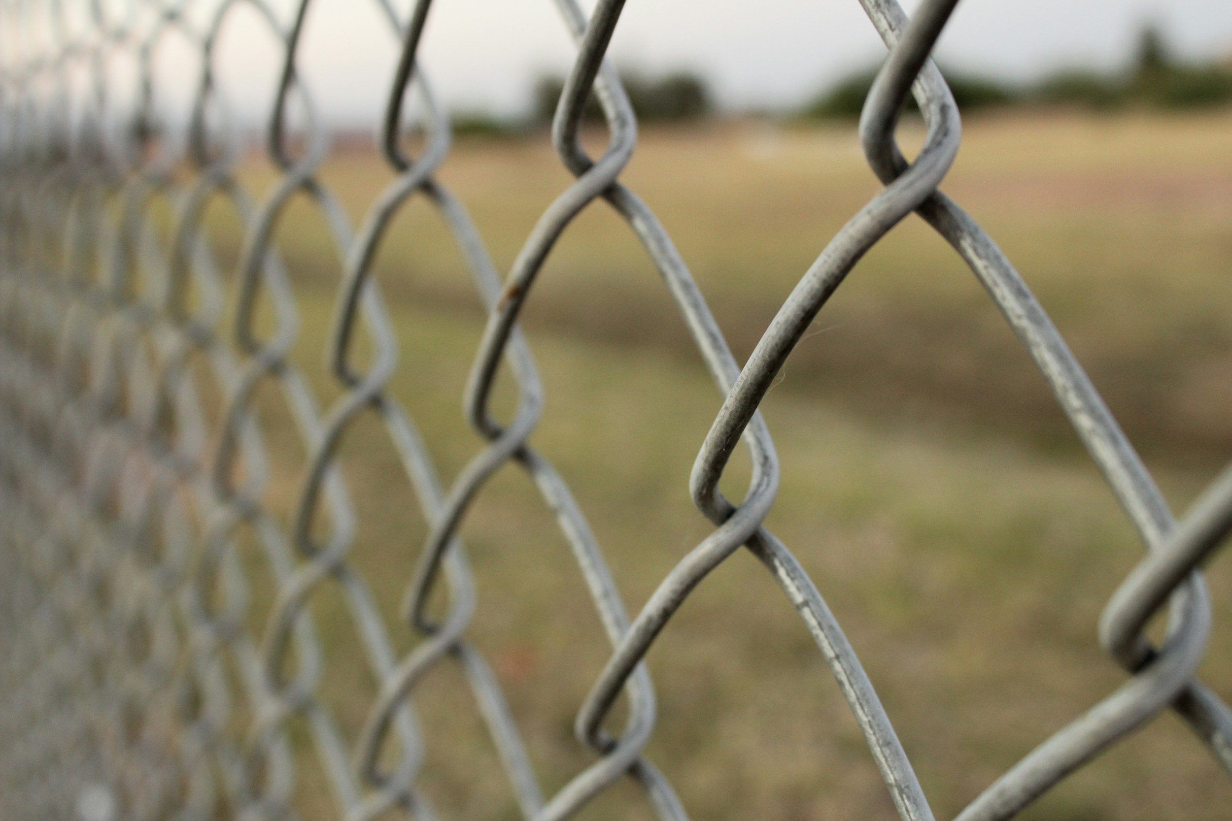 Chain-link fence representing mental blocks, with a grassy field symbolizing mental clarity and calm after guided hypnosis.