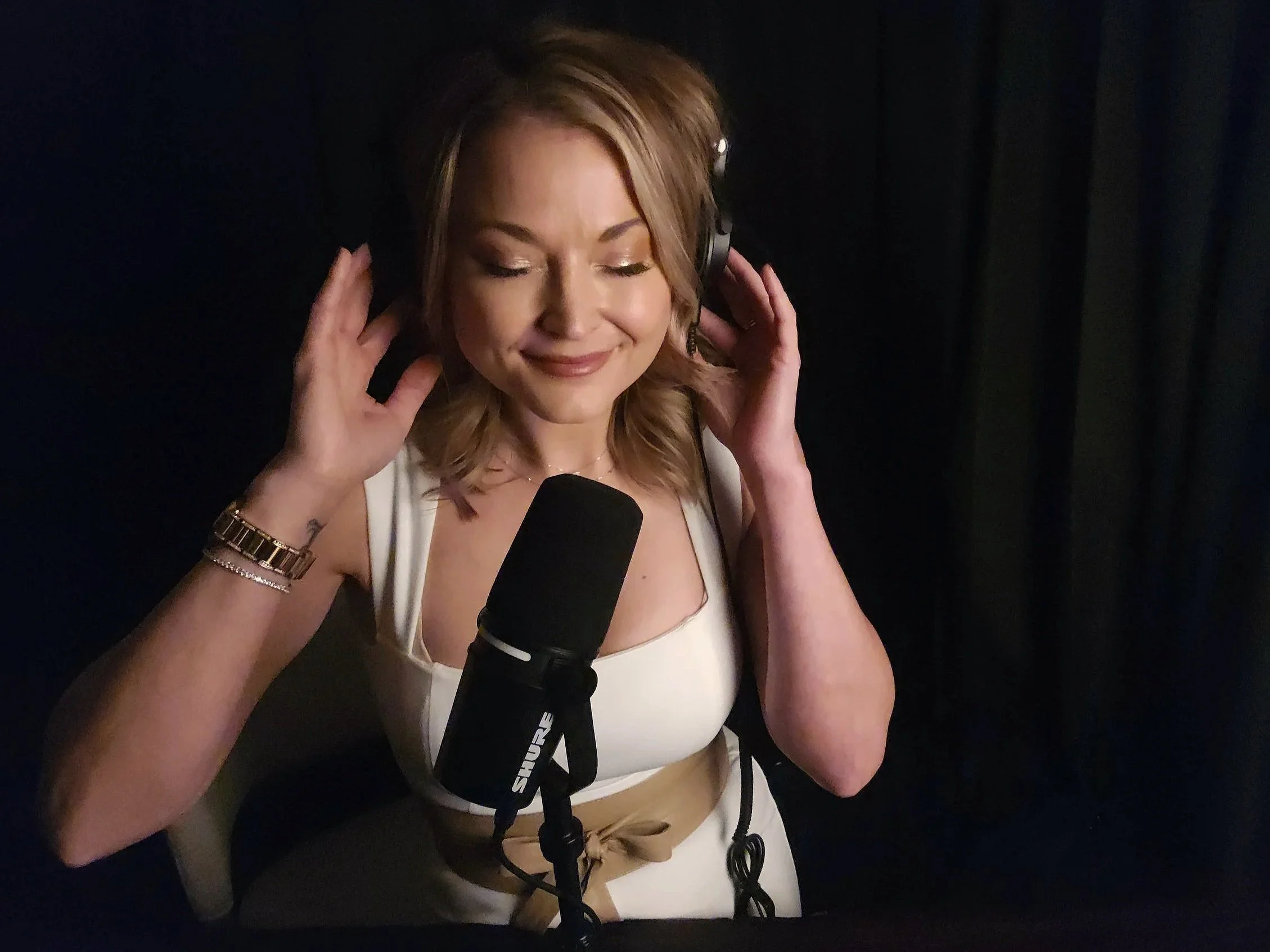 Jasmin Nass wearing headphones and speaking into a microphone, recording guided hypnosis audio for mental clarity and stress relief.