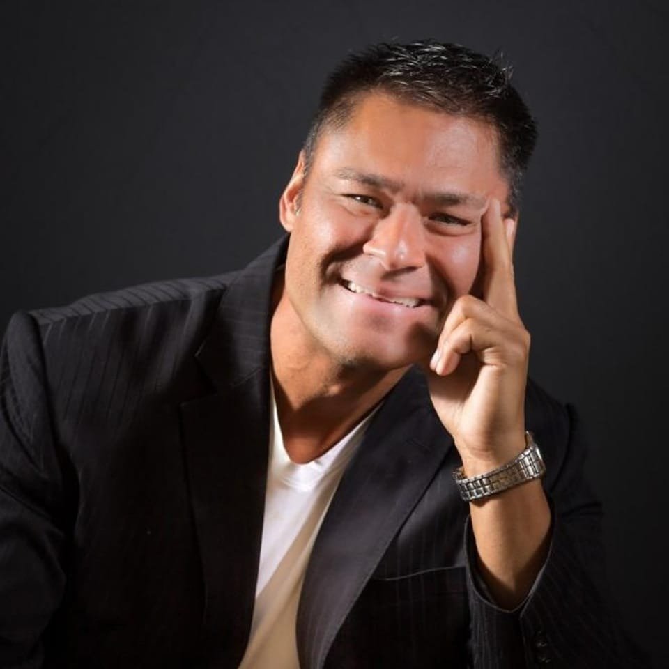 Smiling client in a suit with hand on temple, representing focus, confidence, and calm after guided hypnosis.