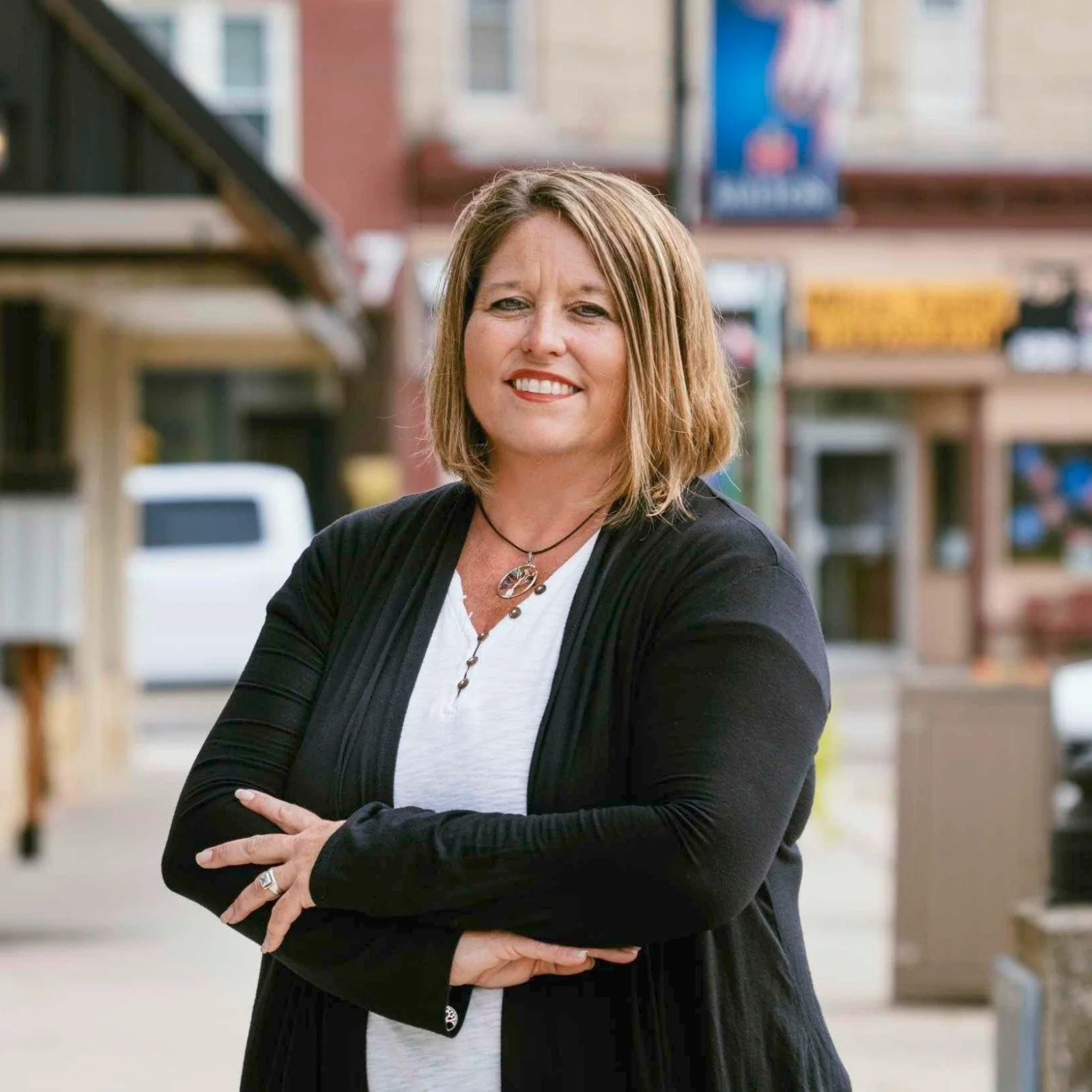 Smiling client standing outdoors on a small-town street, representing confidence, calm, and satisfaction after guided hypnosis.