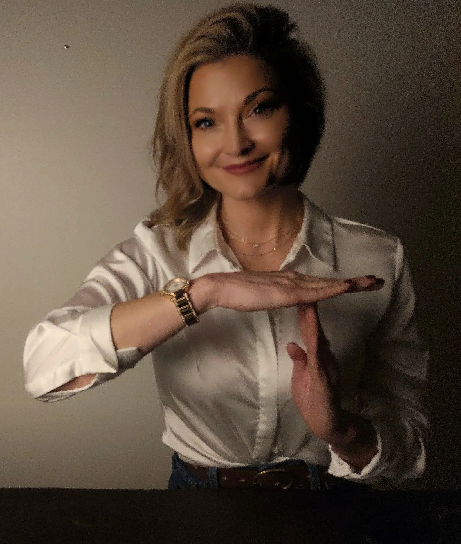 Woman smiling while framing a rectangle with her hands, representing focus, clarity, and a new perspective.