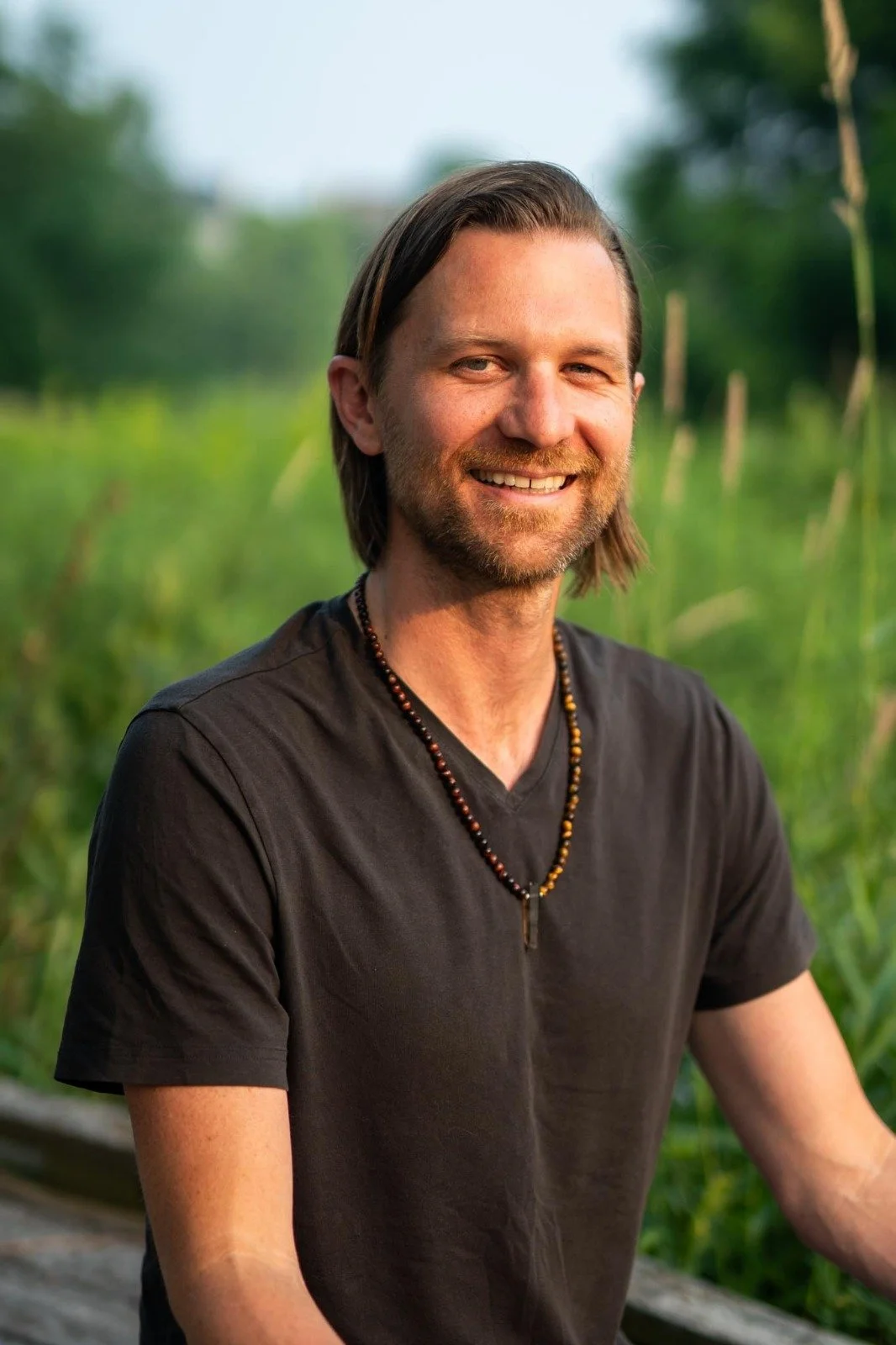 Smiling client outdoors in a natural setting, representing calm, confidence, and emotional balance after guided hypnosis.