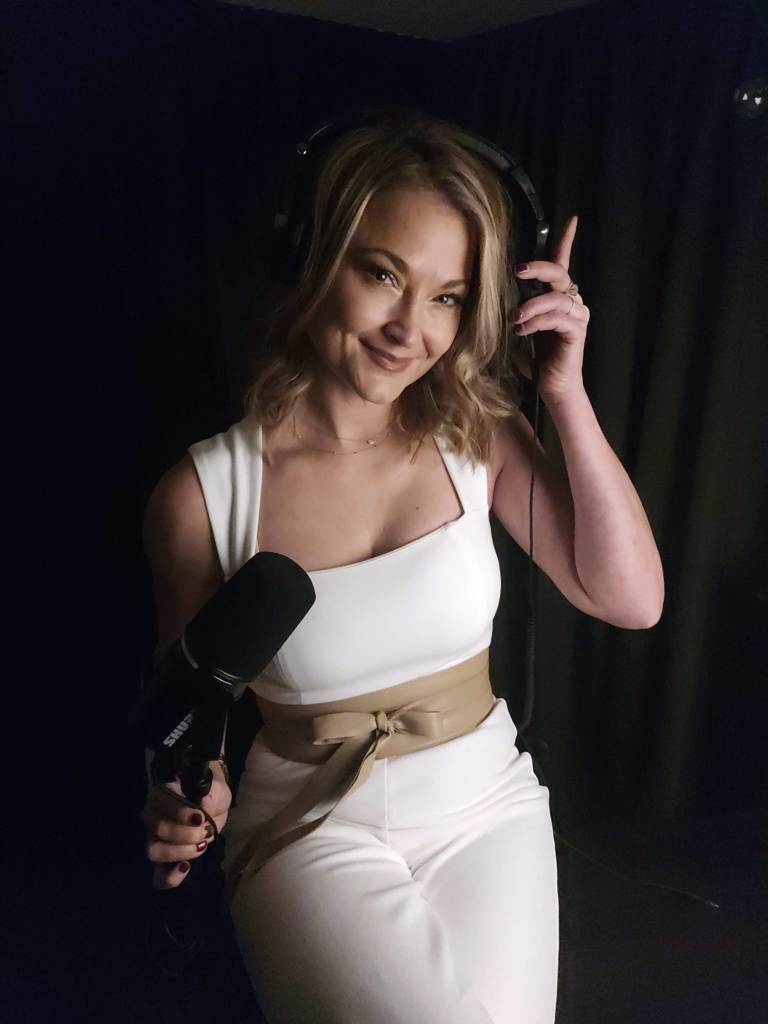 An Elevate Mindworks practitioner holds a microphone and headphones while recording guided mind relief audio.