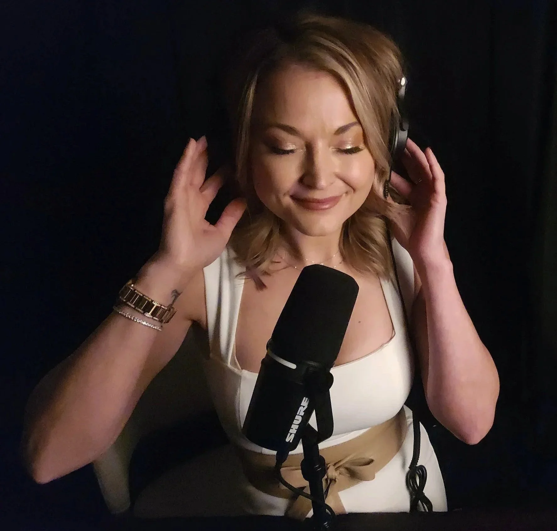 Jasmin Nass wearing headphones and speaking into a microphone, recording guided hypnosis audio for mental clarity and stress relief.