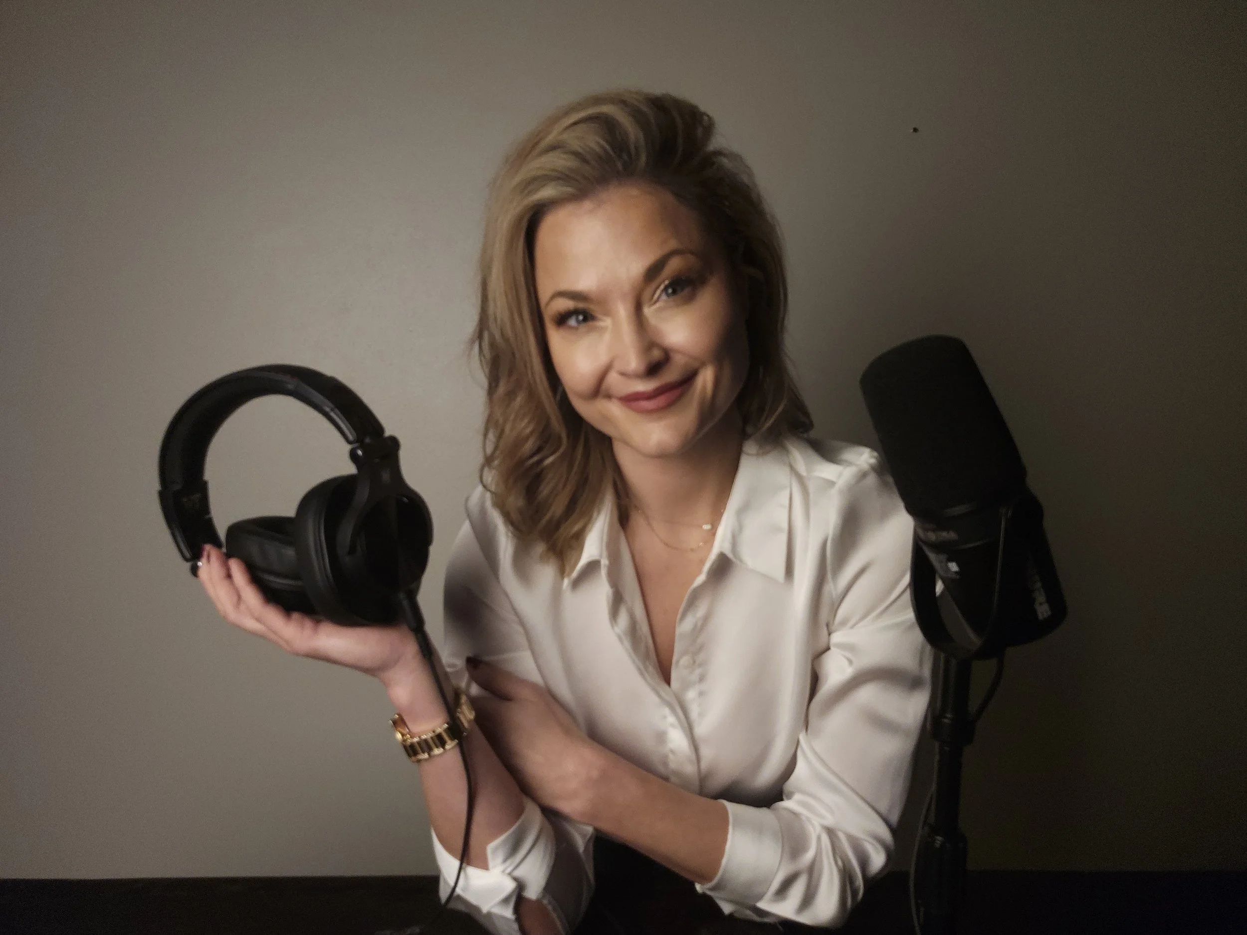 Jaz Nass holding a headset in front of a microphone, representing personalized 1:1 hypnosis and guided mental reset support with Elevate Mindworks