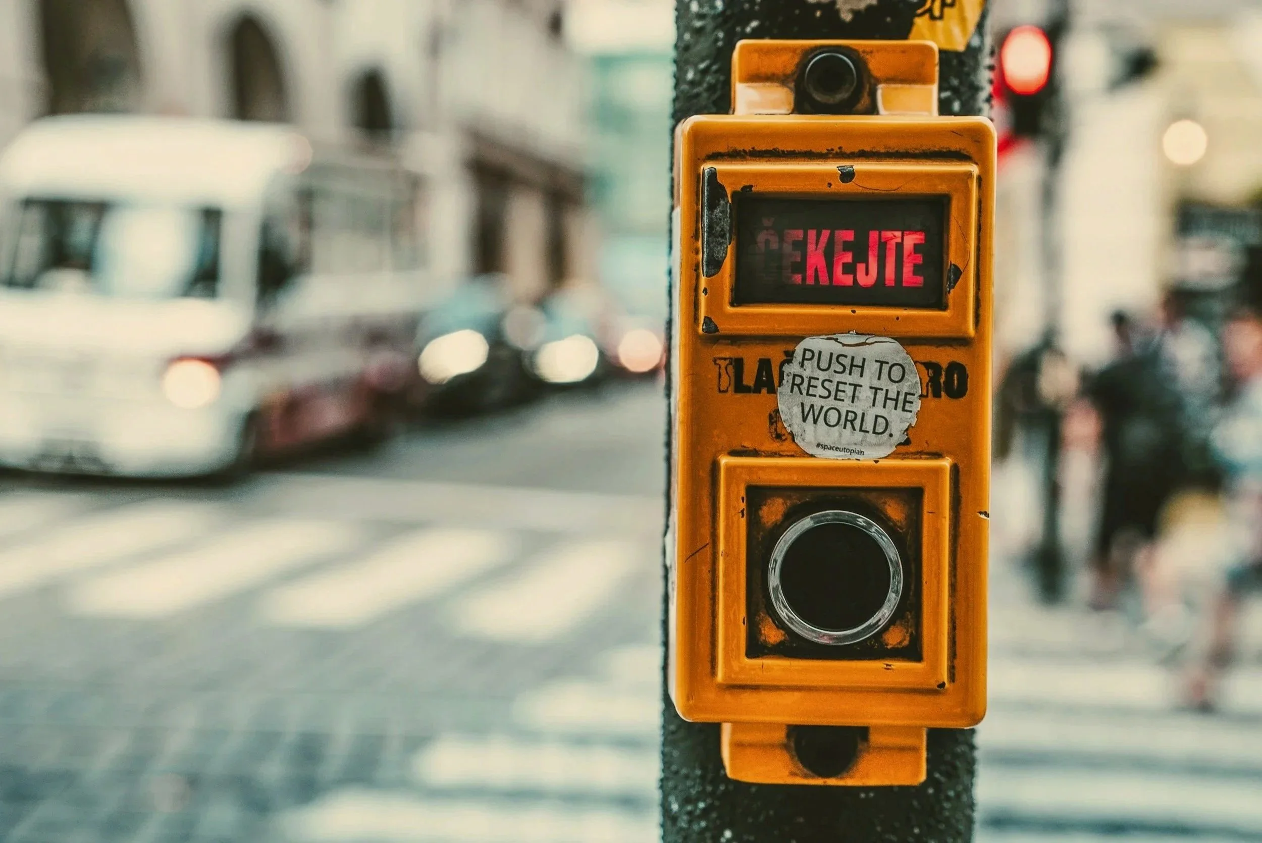Pedestrian crossing button with a message about resetting the world, symbolizing change, choice, and starting fresh.