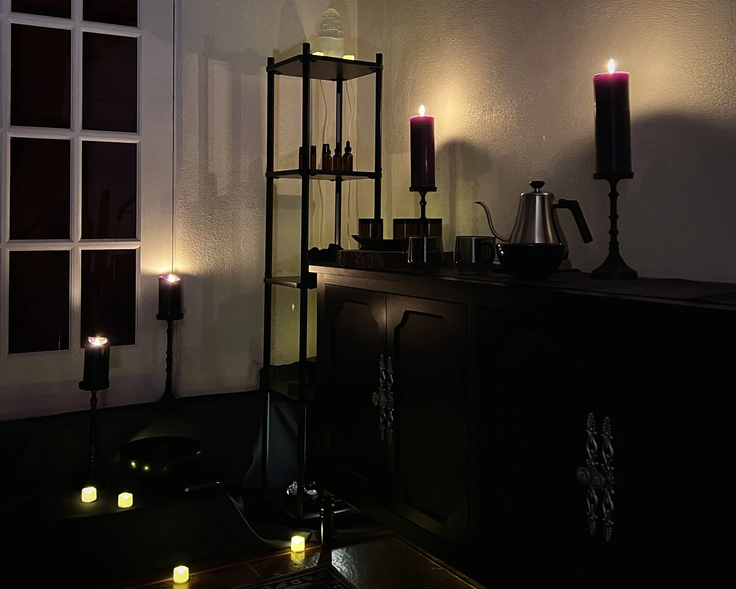 A candle-lit wellness space at Veluna Wellness in Santa Fe with ritual objects, reflecting aesthetic spirituality and the absence of embodied regulation.