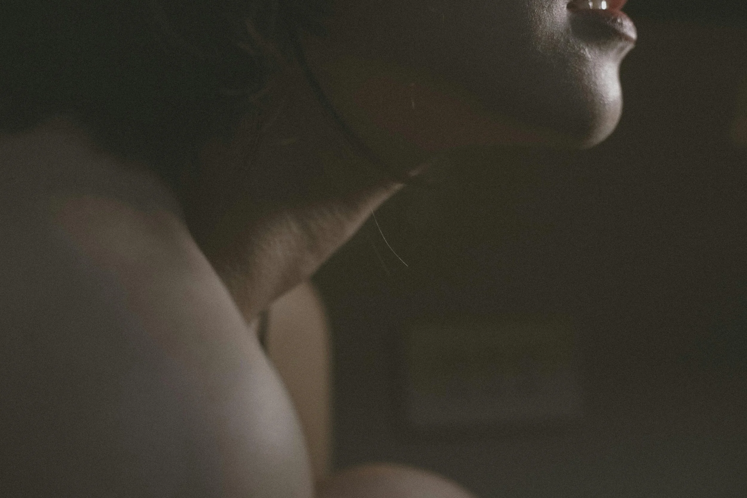 Close up of a woman's throat and jaw lit softly from the side against a dark background, representing the Voice Return Practice