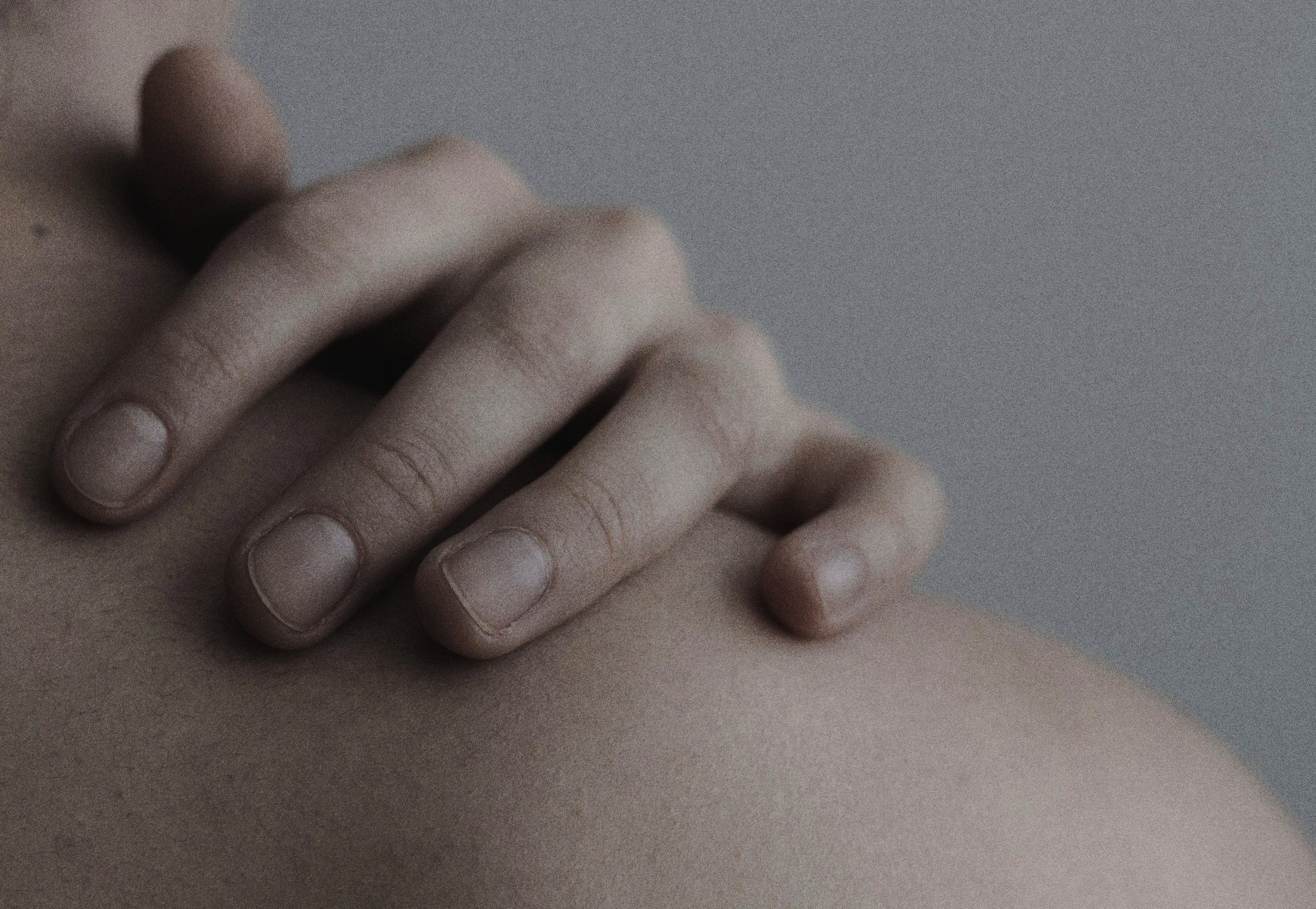 Close-up of a hand resting gently on a shoulder in soft shadow, symbolizing self-support and nervous system softening under the full moon.