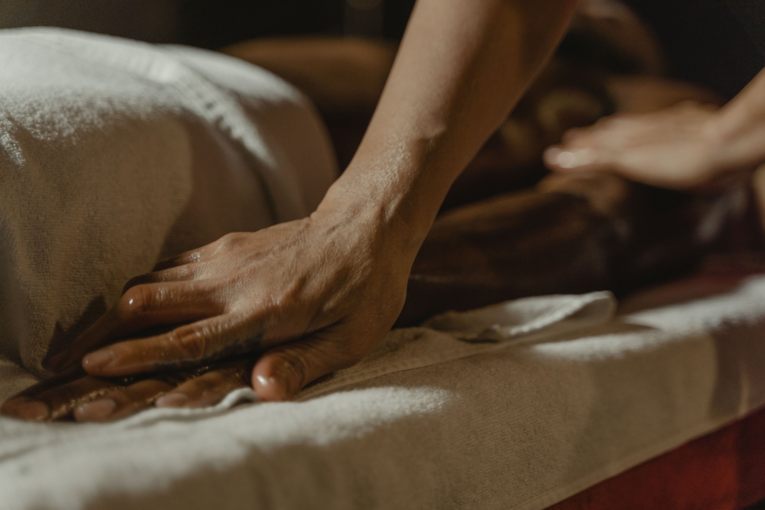 Hands performing bodywork on a client's back, illustrating the boundary between massage therapy and psychotherapy.