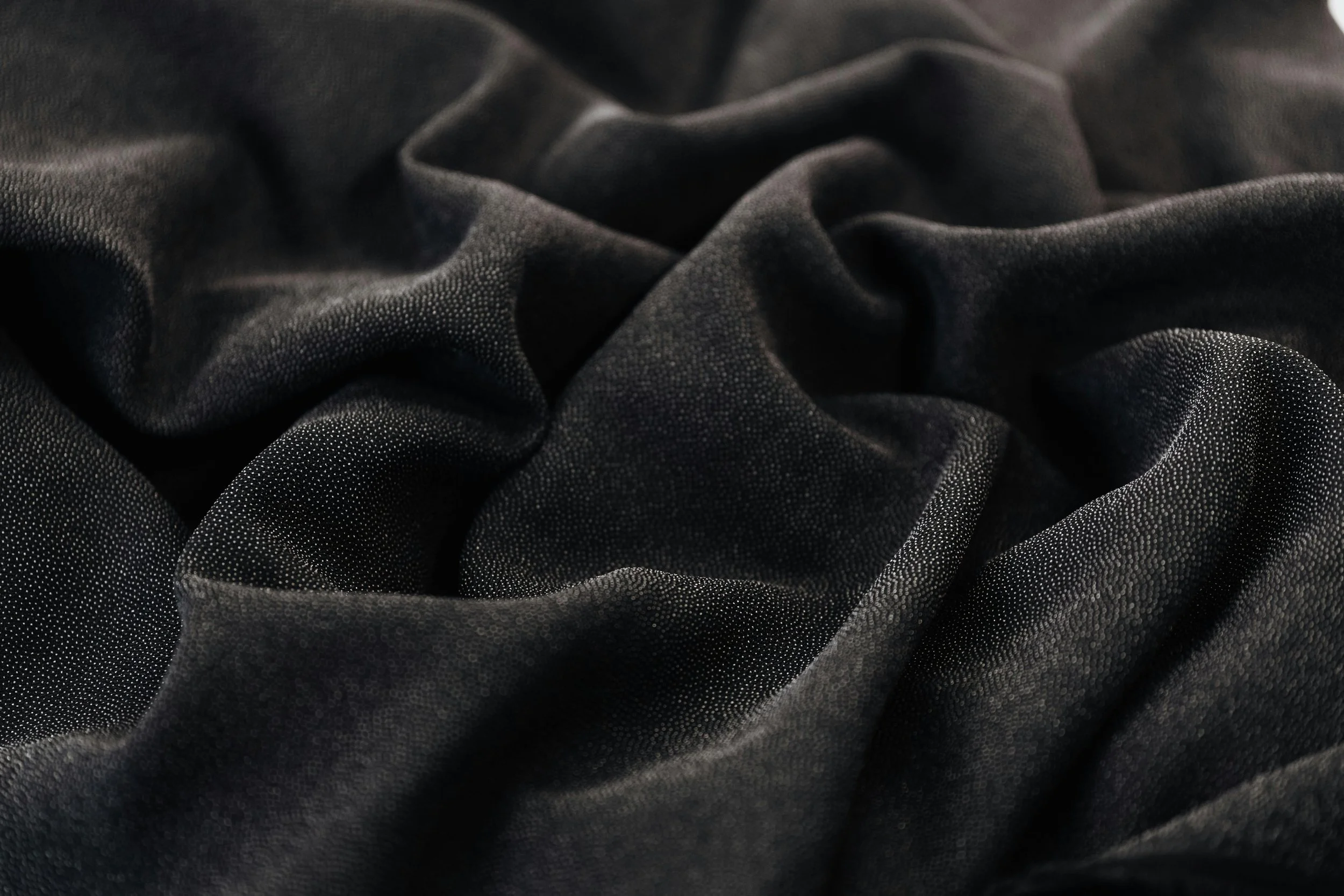 Dark, soft, folded fabric with subtle texture, evoking a sense of calm and safety.