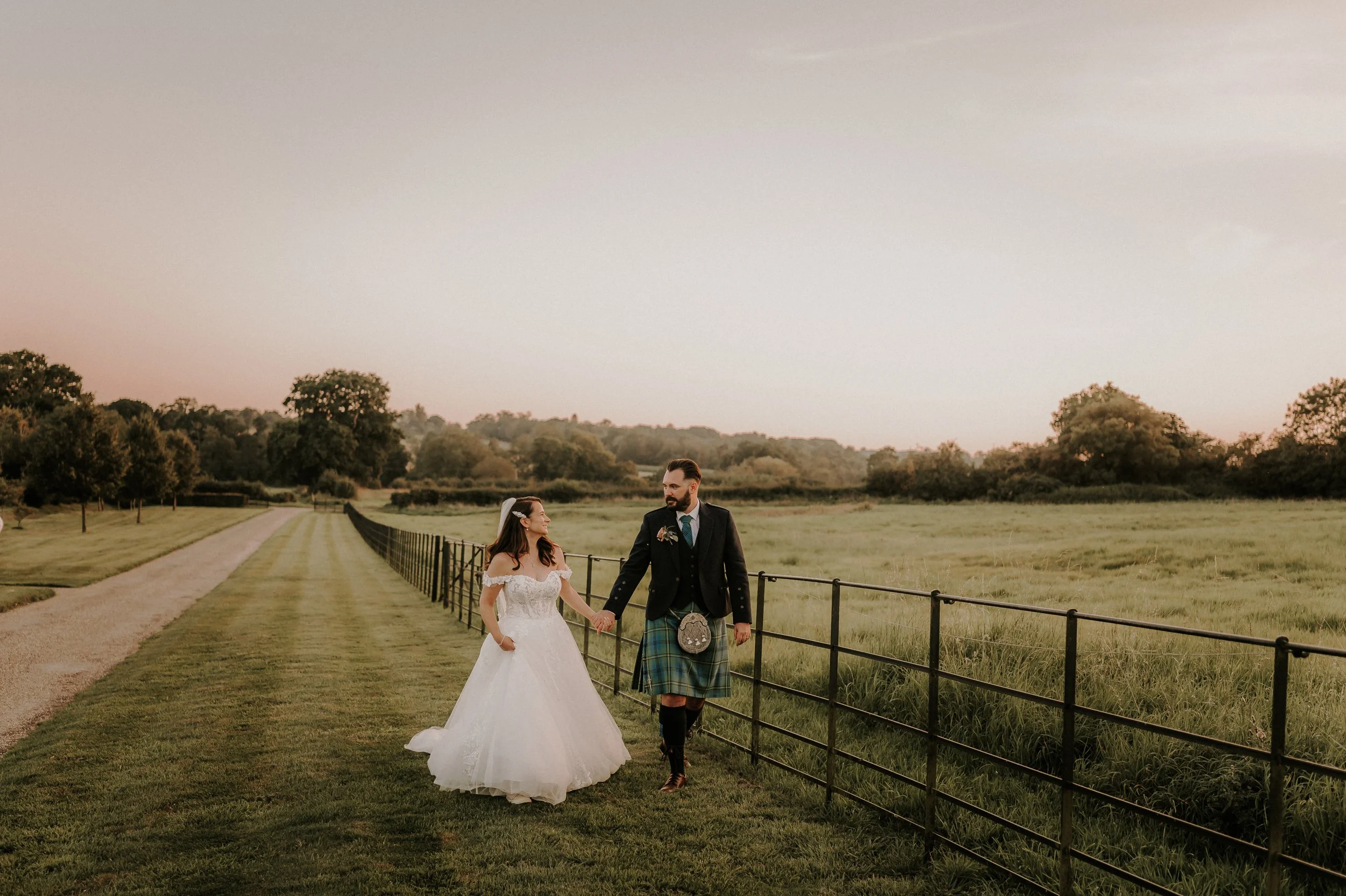 Bride and groom walking through country estate gardens