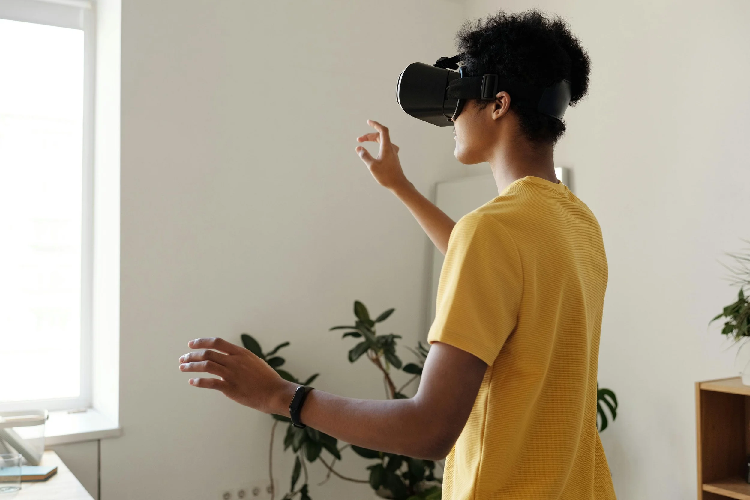 Young man is wearing a VR headset and using his hands to control it.