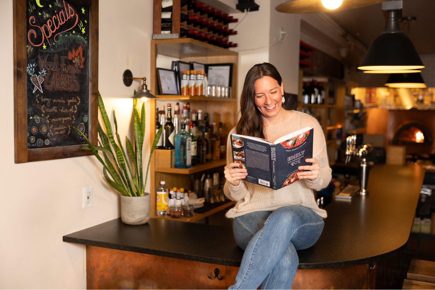 Emily sitting on counter reading cookbook