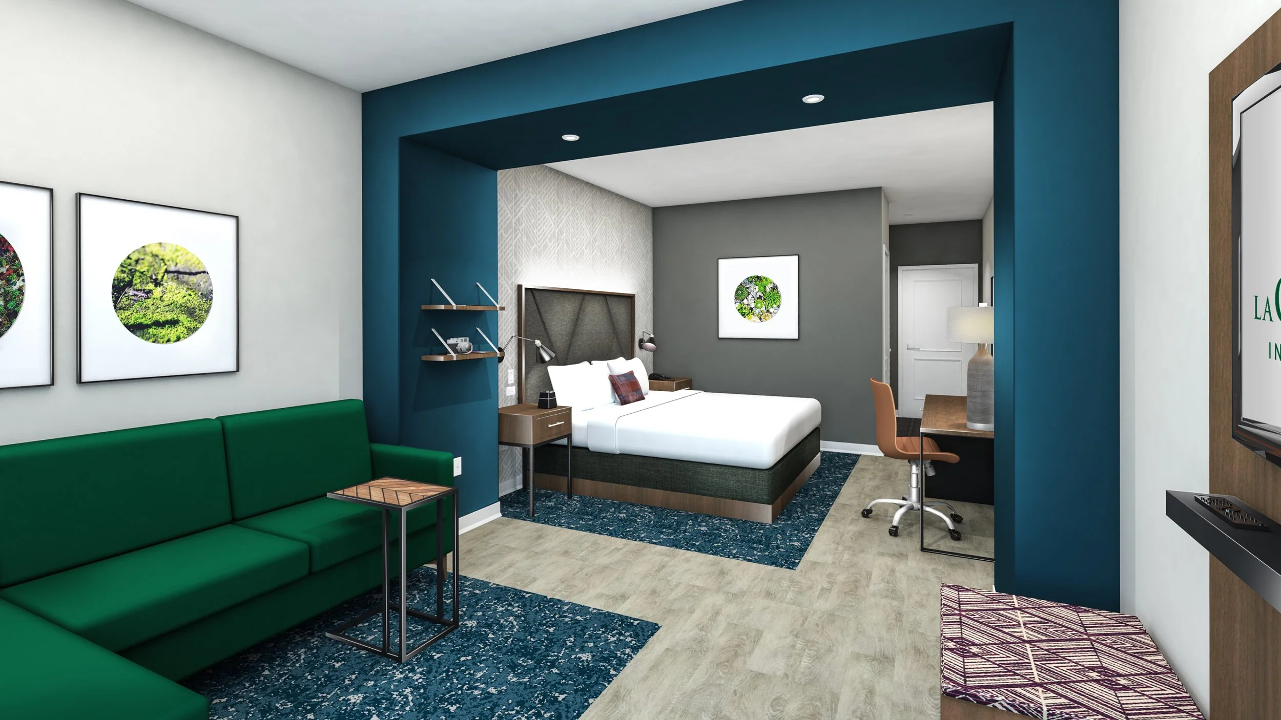 Modern hotel room with a sitting area, green sofa, and a separate bedroom with a bed, artwork, and workspace.