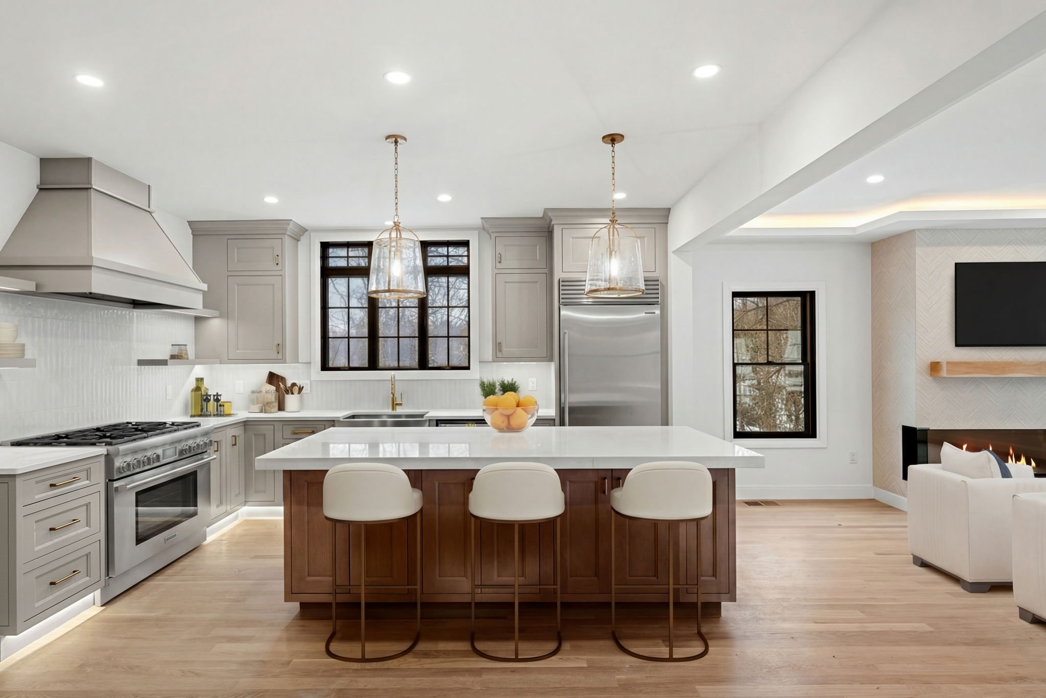 A modern kitchen featuring luxury appliances, a center island, and a gas fireplace visibile in the adjoining living space.