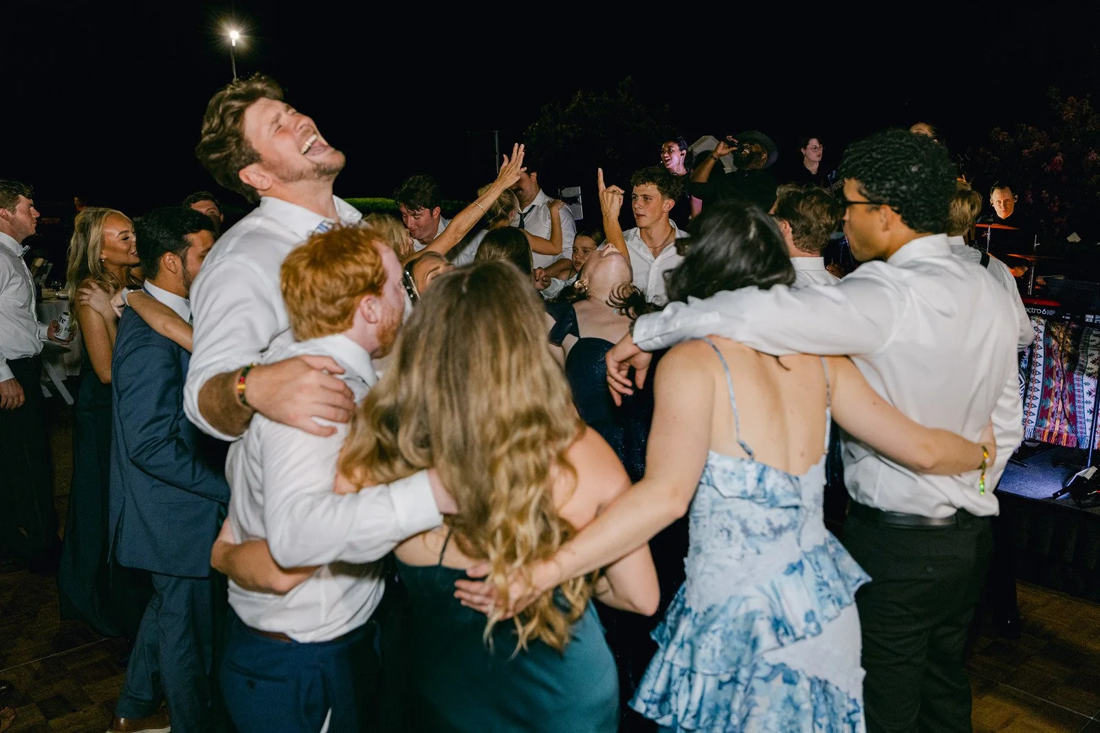 A bride and groom walking out of a building at night, surrounded by friends holding sparklers, celebrating their wedding.