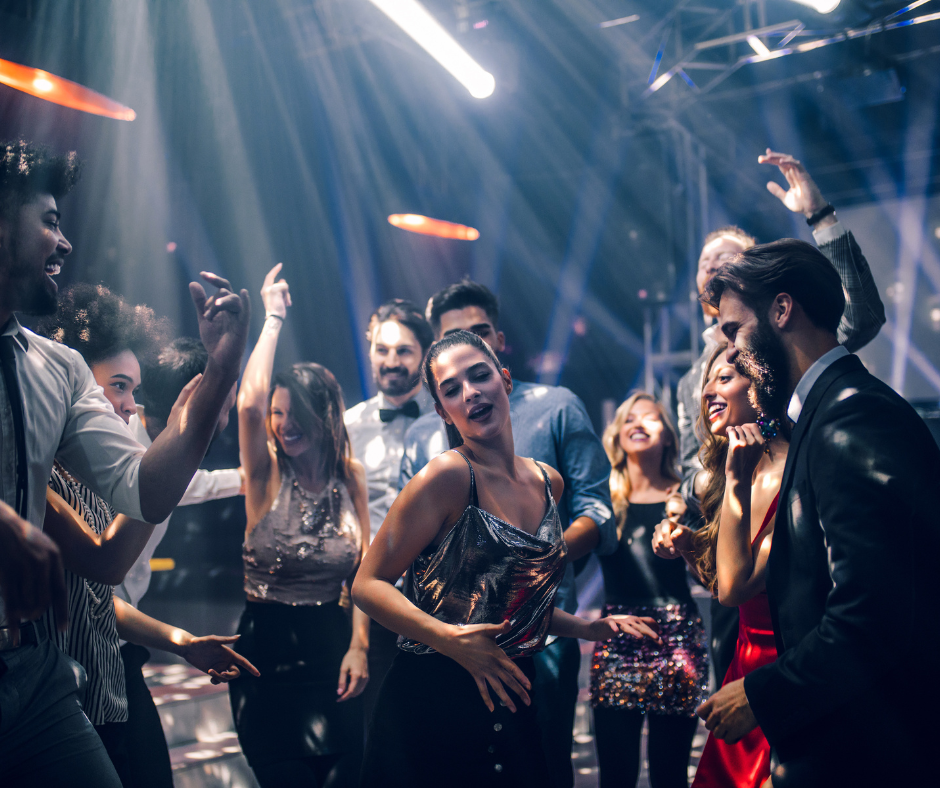 People dancing and having fun at a party with colorful lights.