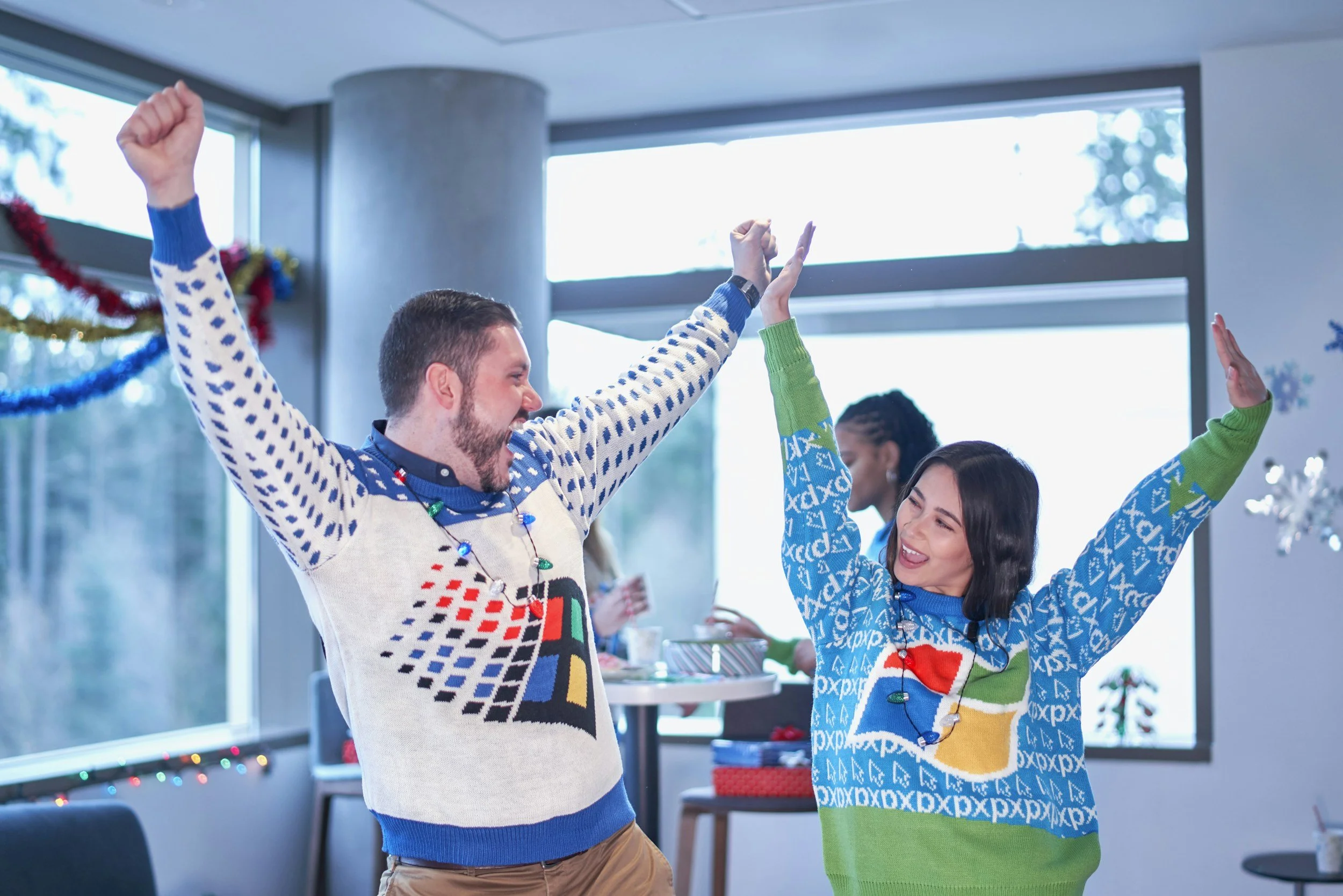 People celebrating and dancing indoors during a holiday party, decorated with festive ornaments and lights.