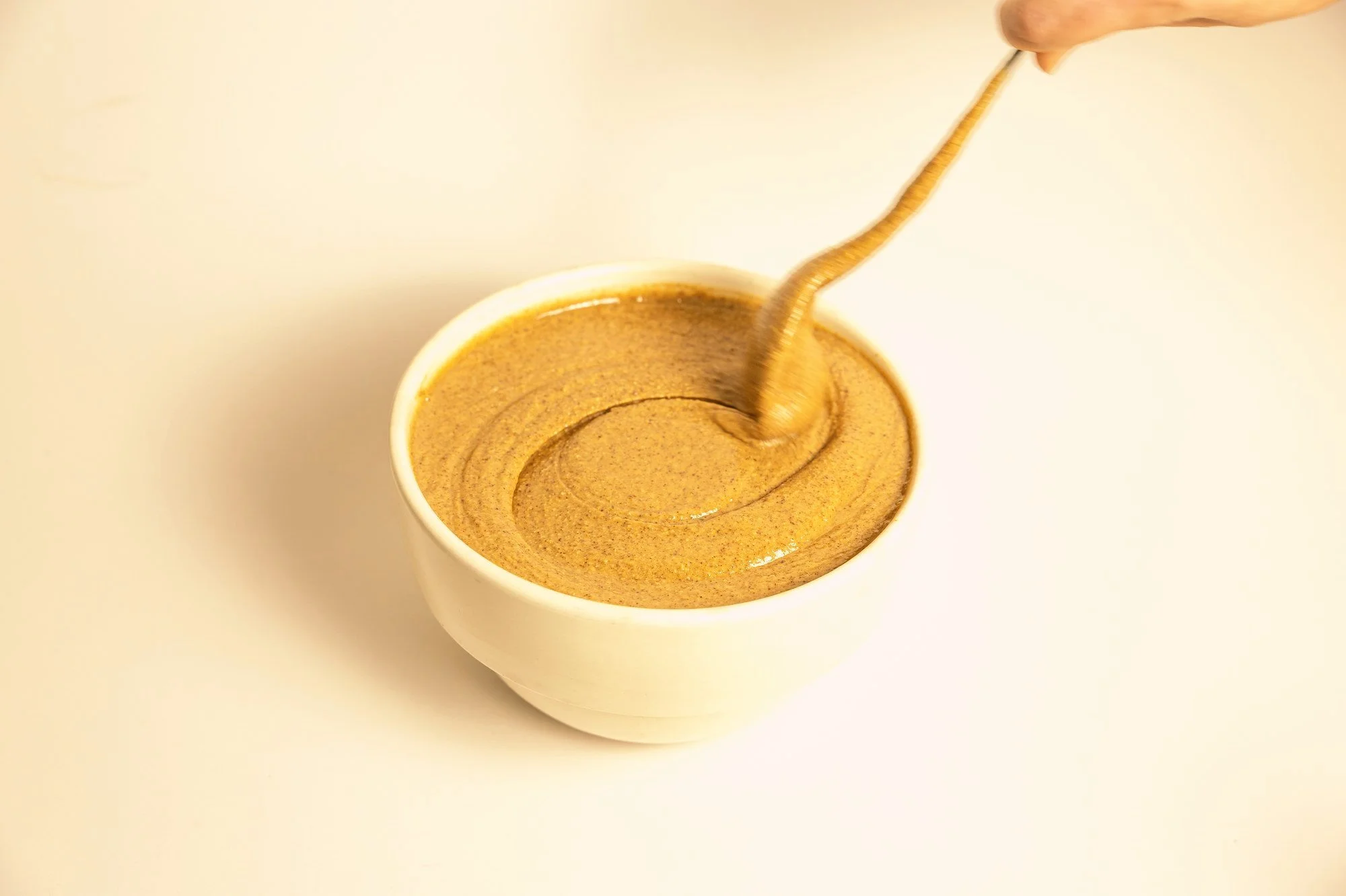 Almond butter in a bowl with a spoon lifting it