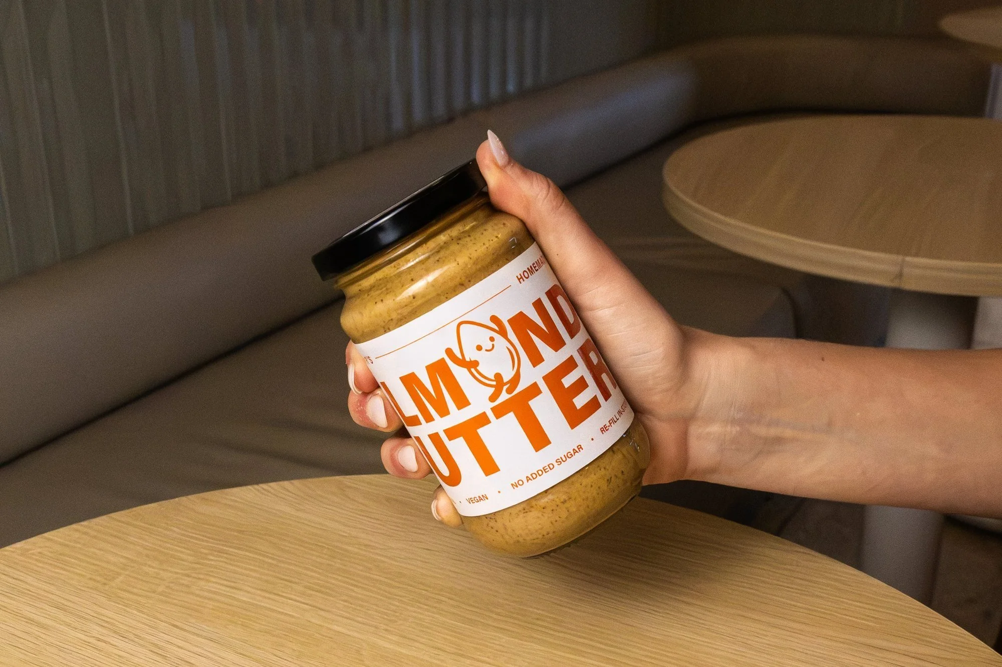 Hand holding a jar of Blitz Bar almond butter inside a Blitz Bar store in Melbourne