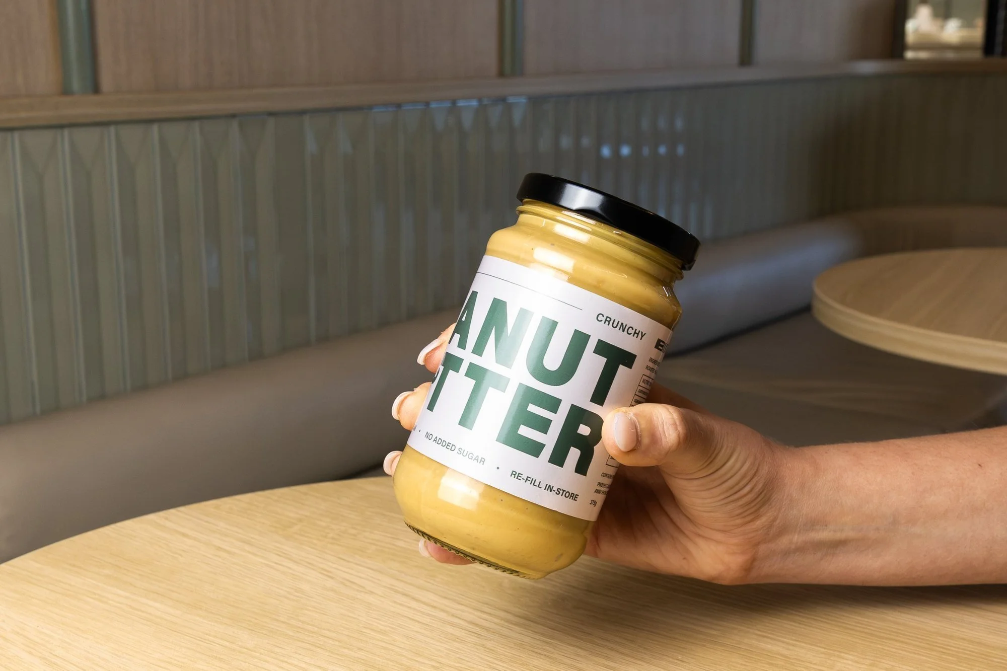 Hand holding a jar of Blitz Bar crunchy peanut butter inside a Blitz Bar store in Melbourne